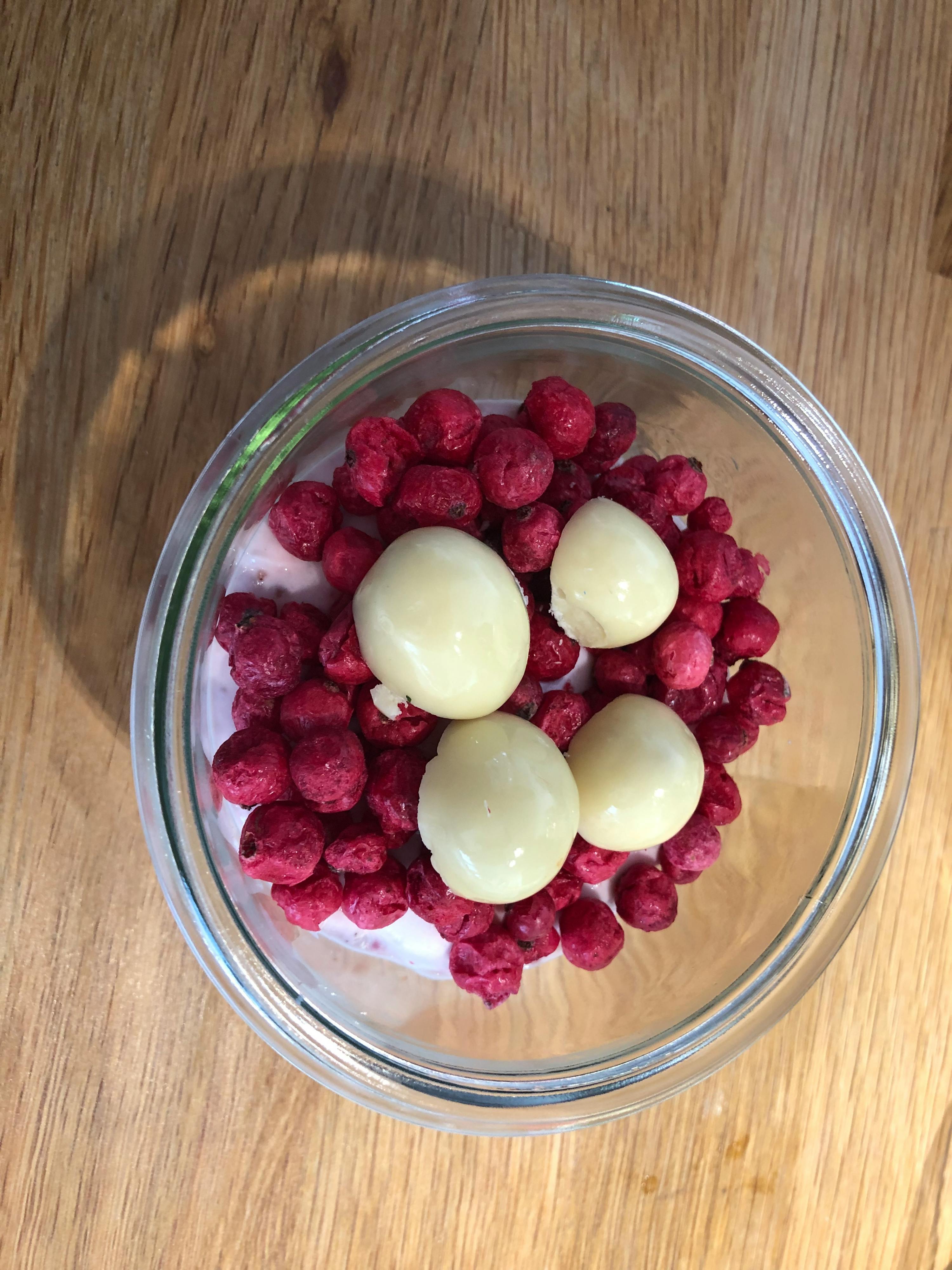 a glass bowl filled with red berries and white chocolate balls