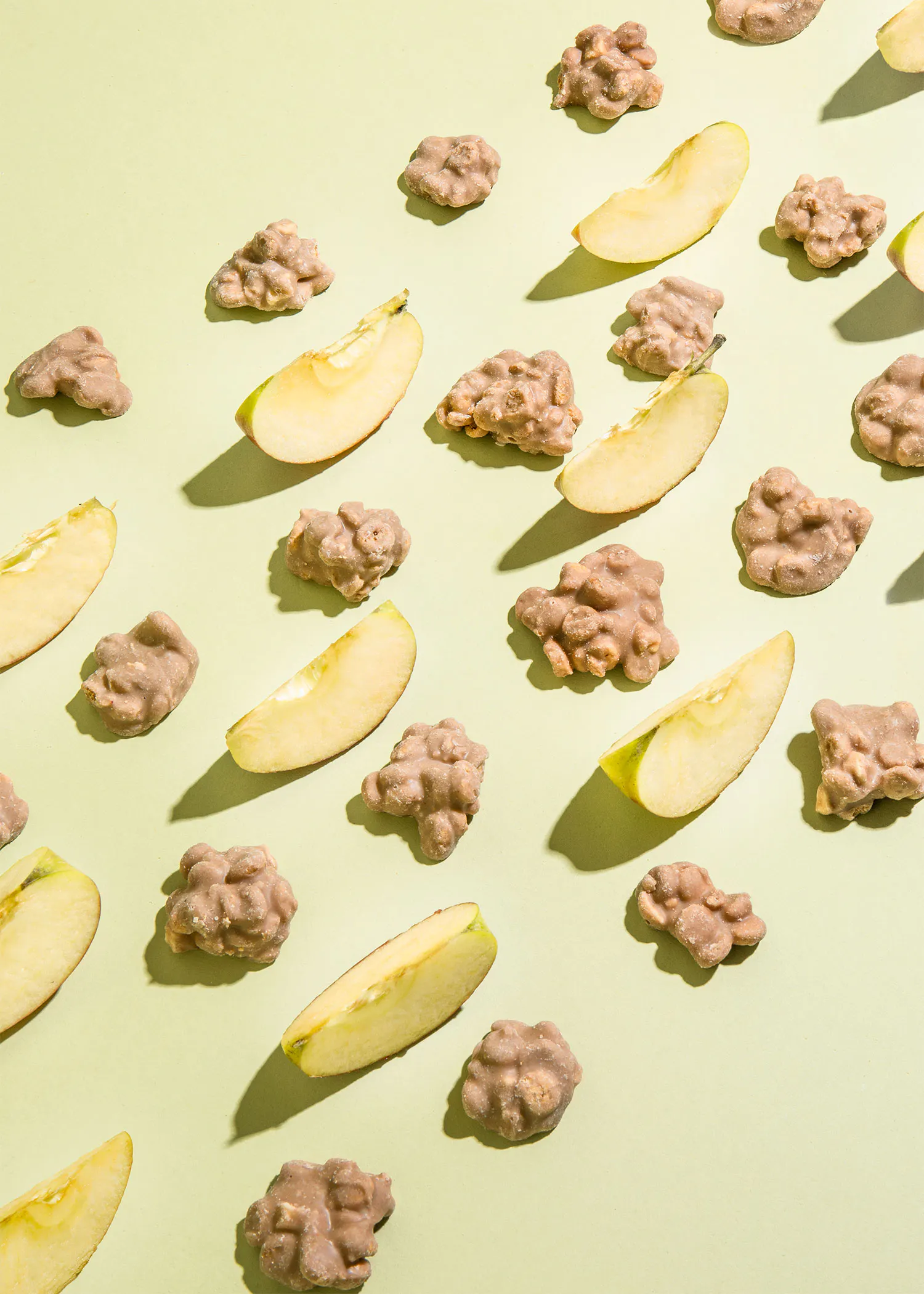 des tranches de pomme et des noix enrobées de chocolat sur un fond vert