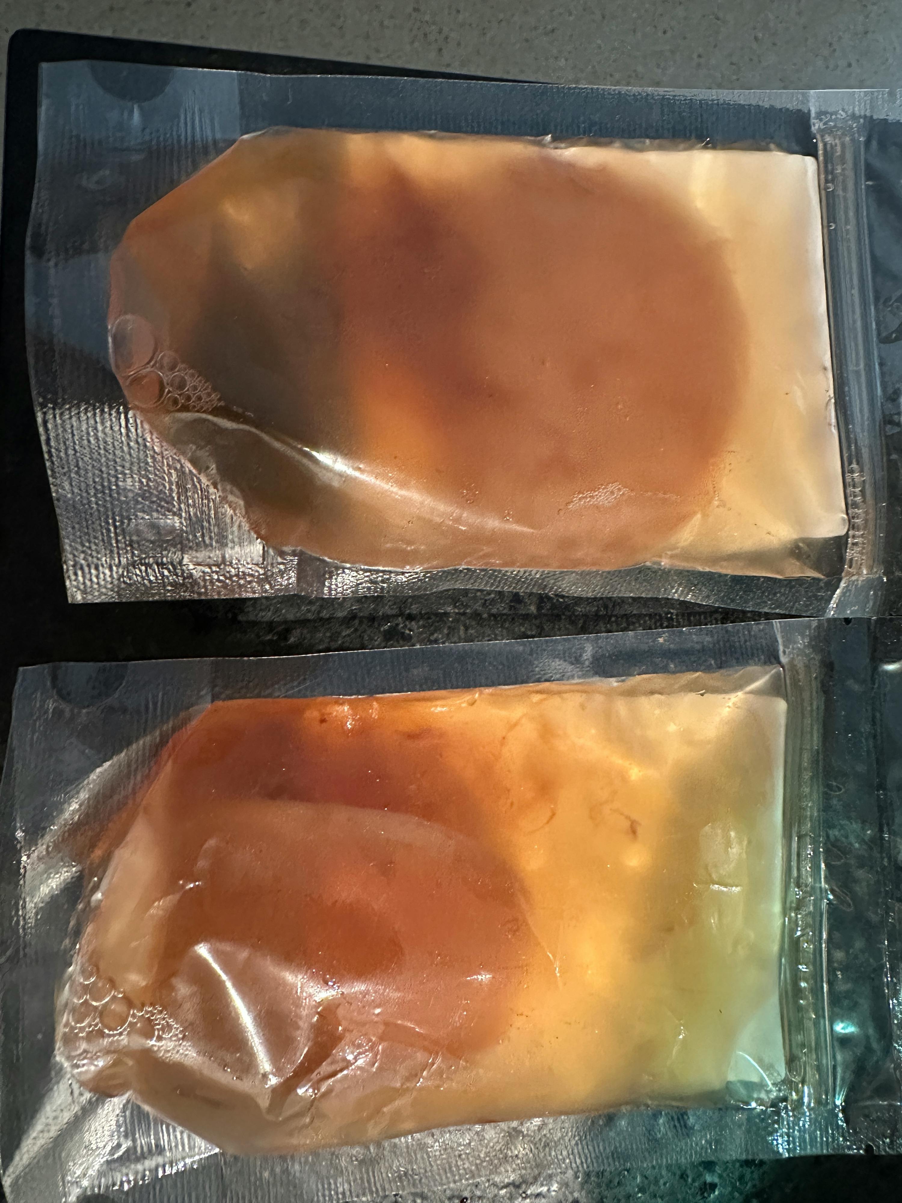 two bags of food are sitting on a table and one of them says ' chicken ' on it