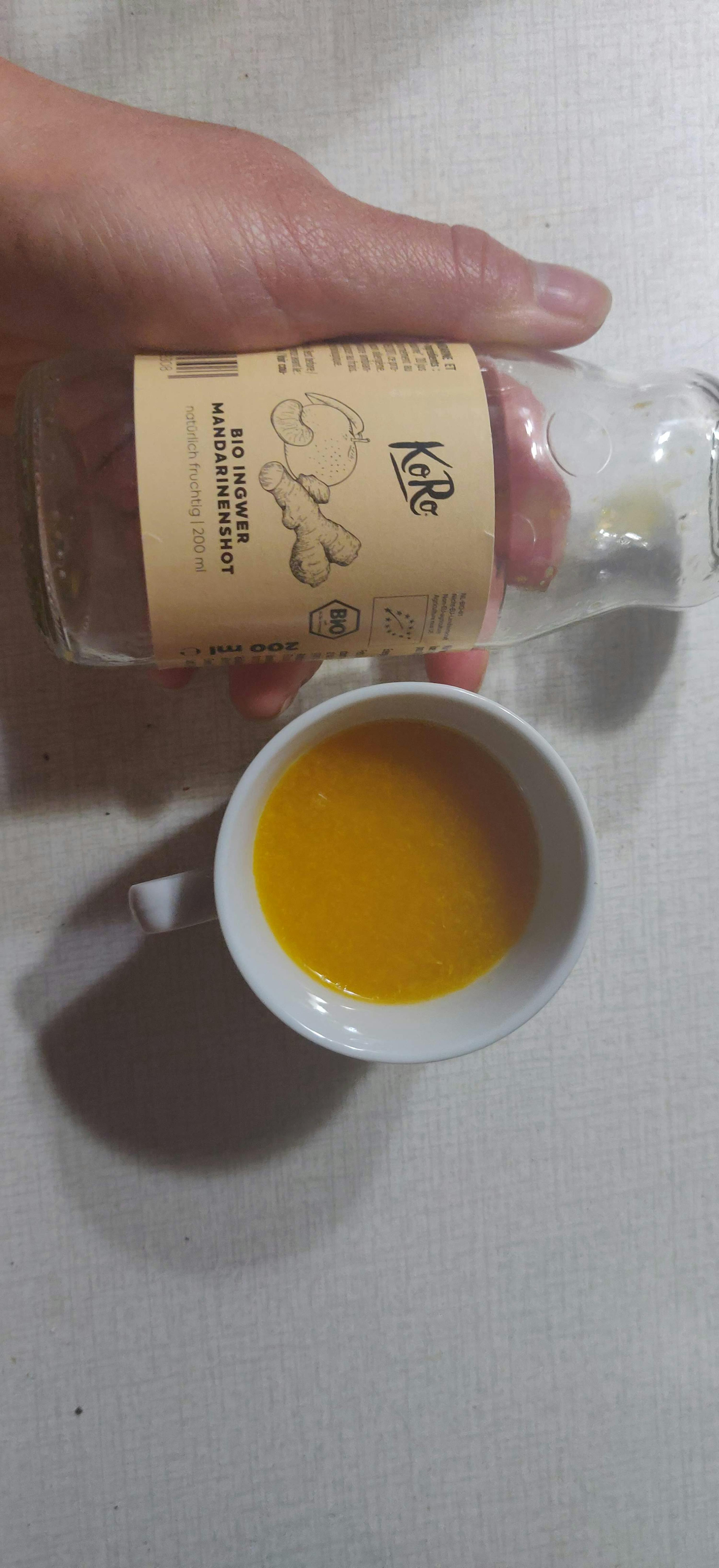 une personne tient une bouteille de bio ingwer mandarinershot
