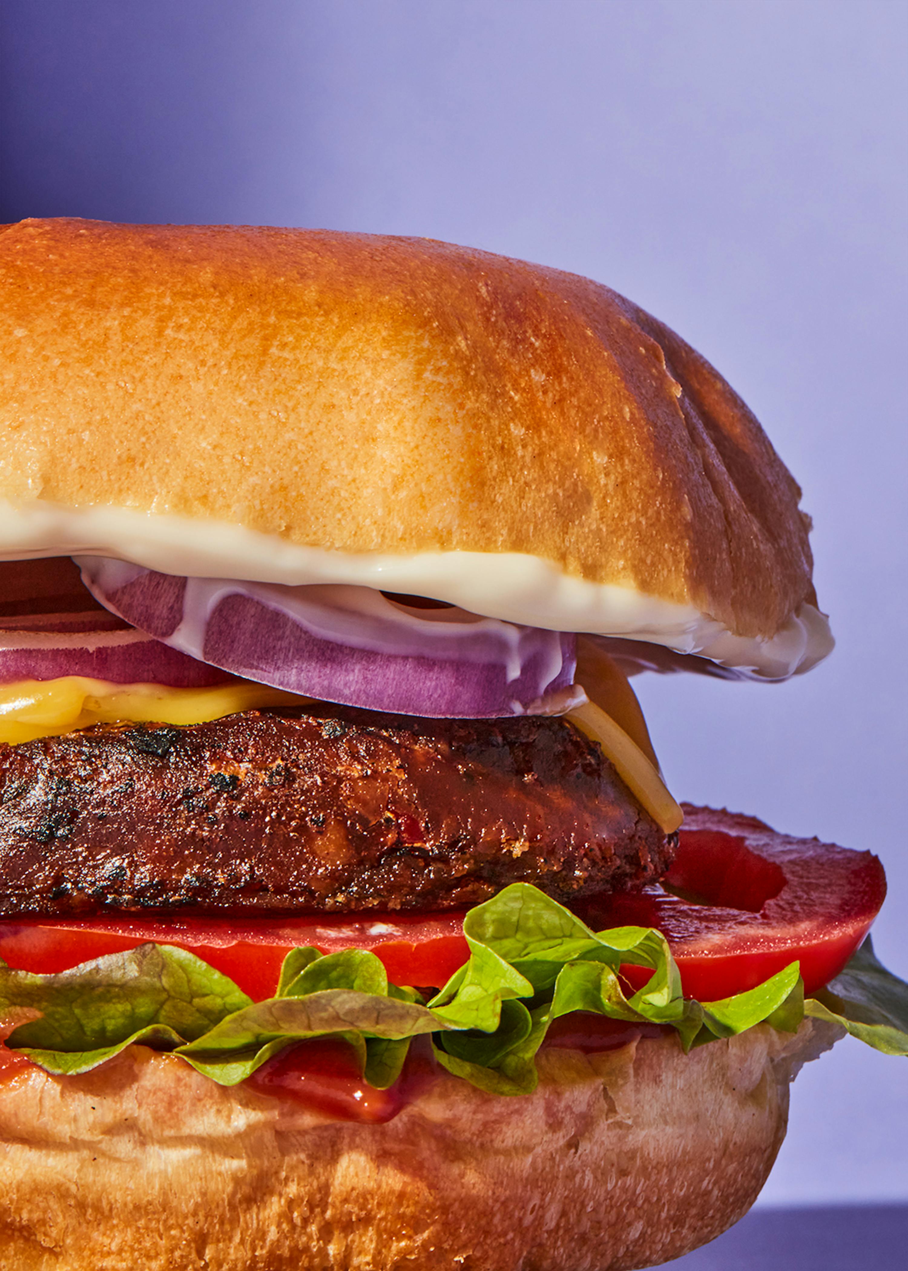 un primer plano de una hamburguesa con queso tomate y cebollas