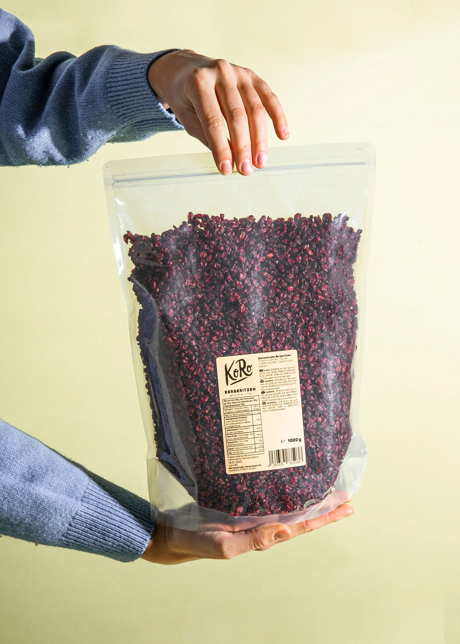 une personne tient un sac en plastique rempli de baies rouges