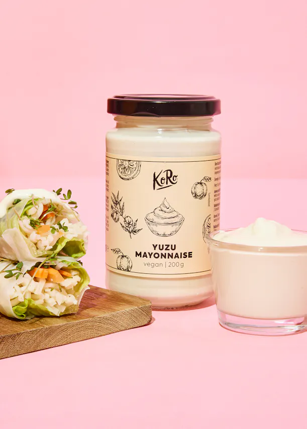 un bocal de mayonnaise végétale avec un sandwich sur une planche à découper