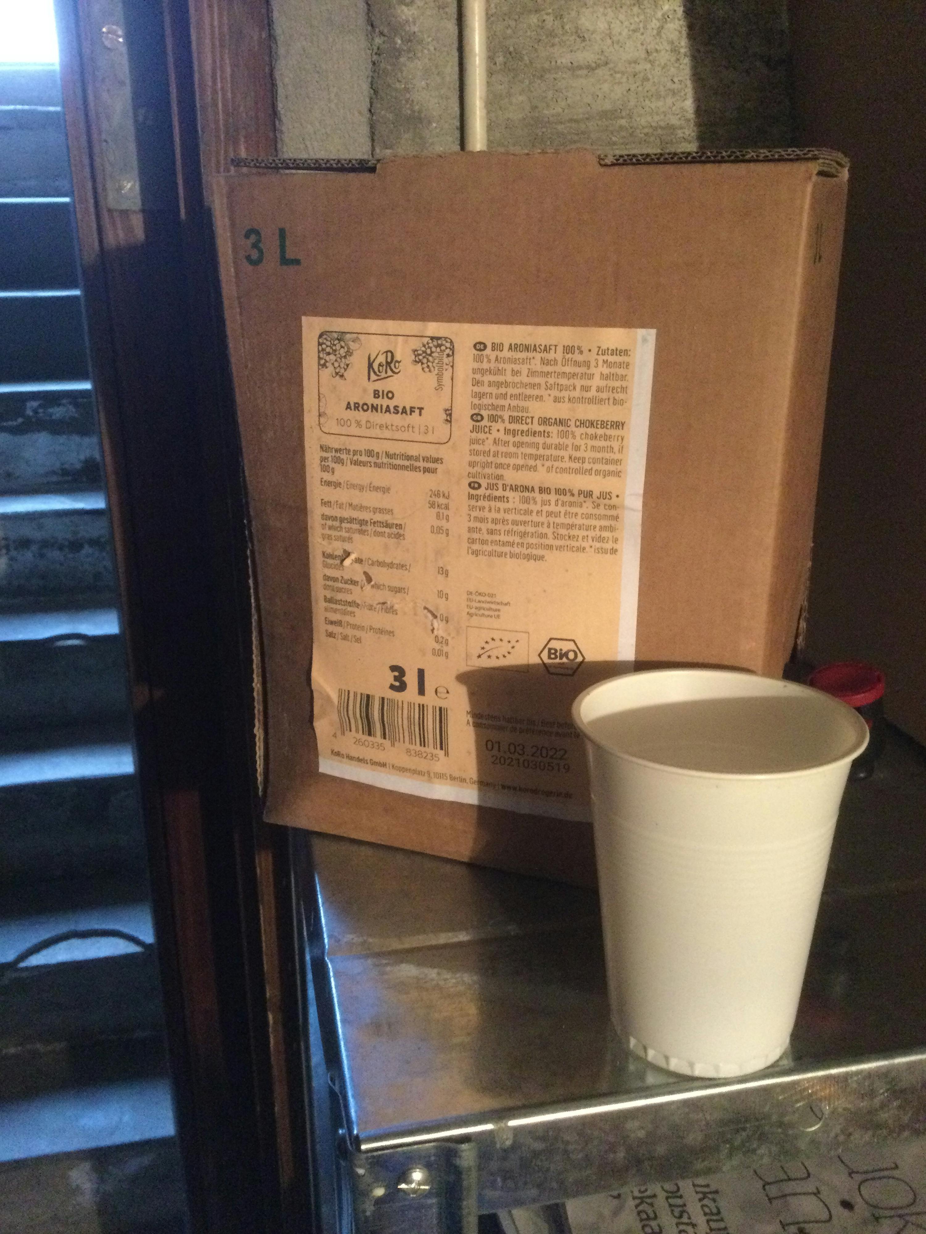 une tasse blanche est posée sur une boîte de jus de pomme bio