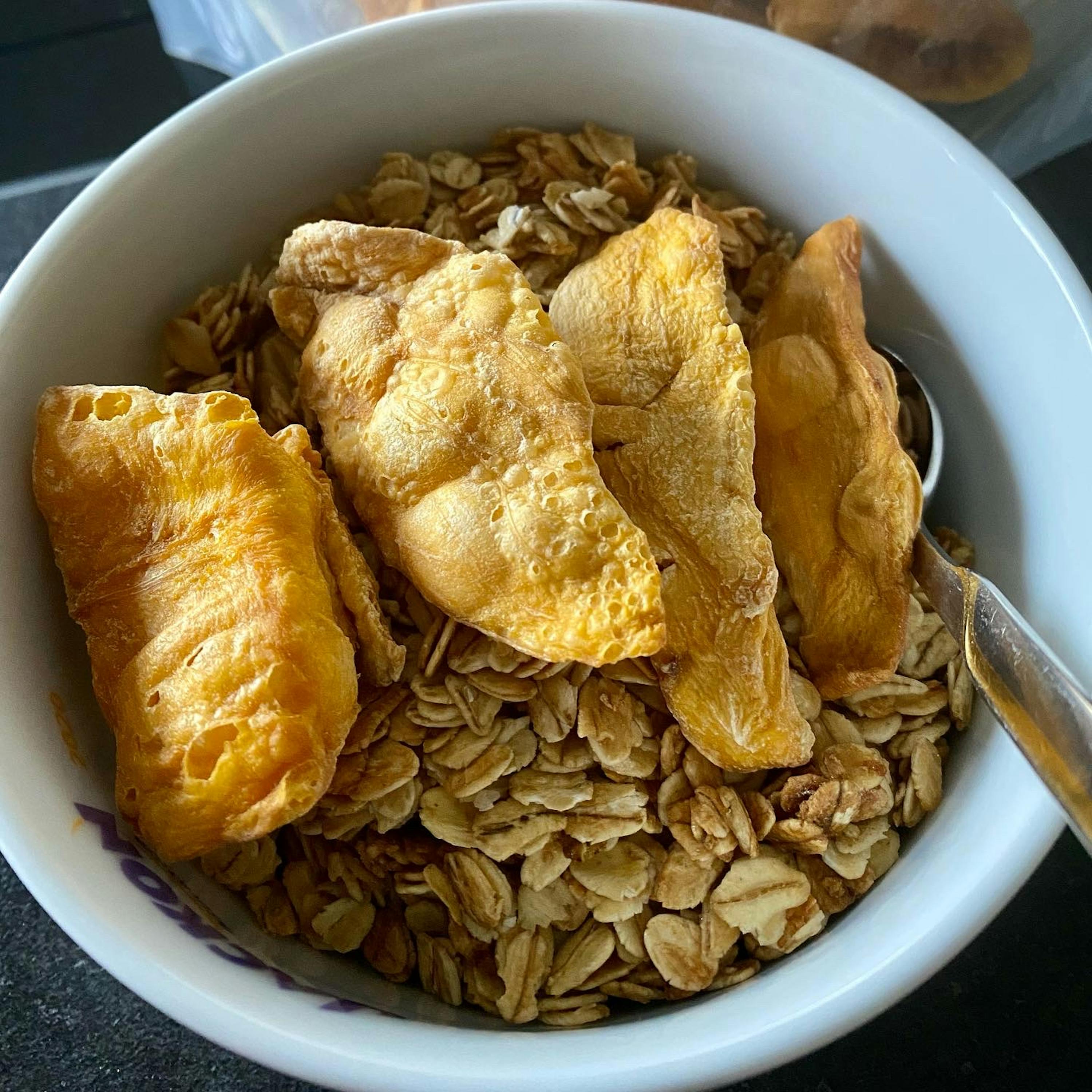 a bowl of granola with dried fruit and a spoon in it