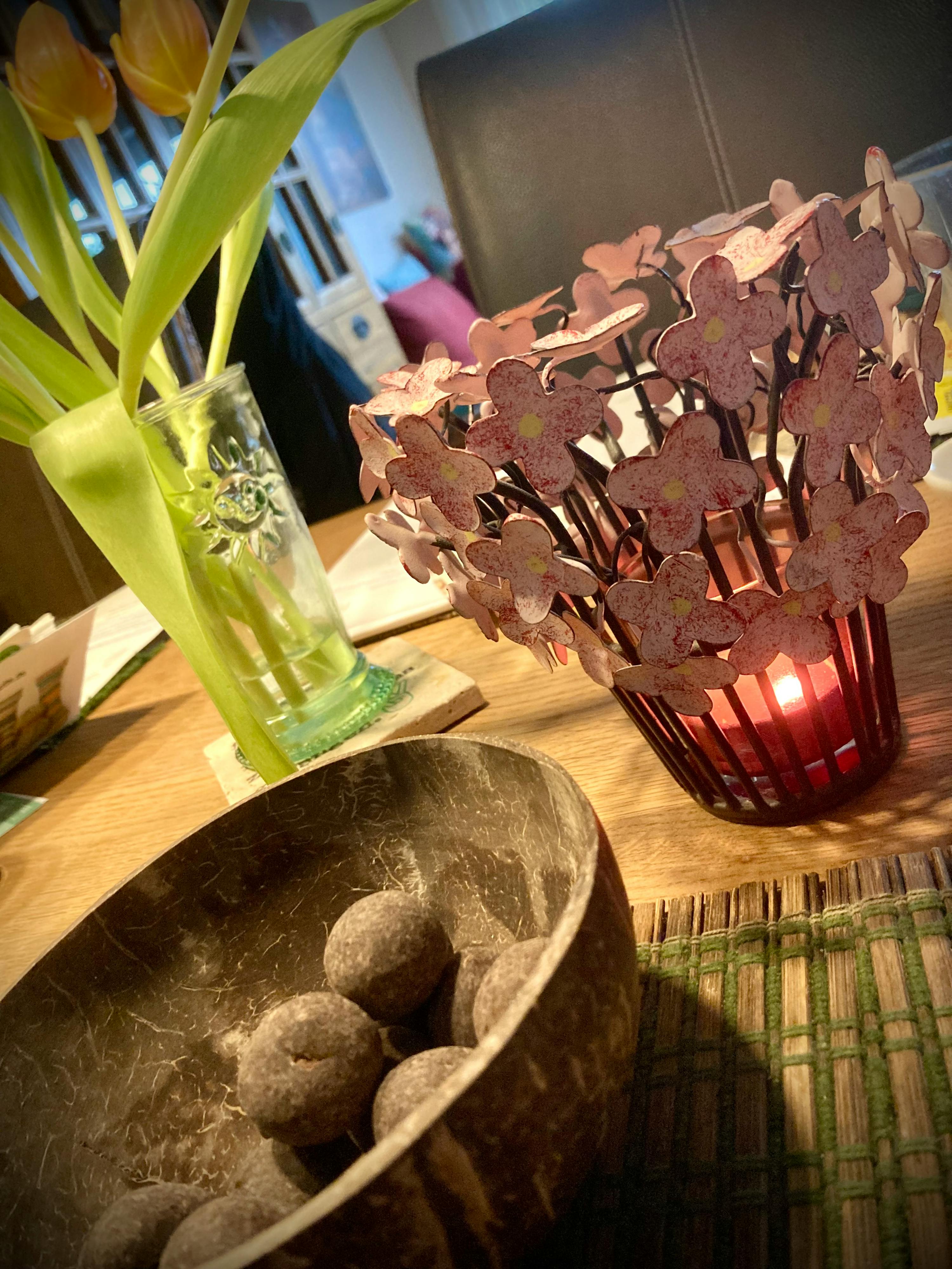 a bowl of chocolates sits on a table next to a candle holder with pink flowers