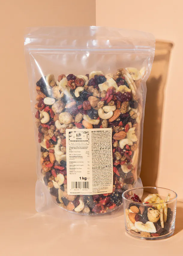 un sac de noix et de fruits se tient à côté d' un bol de noix