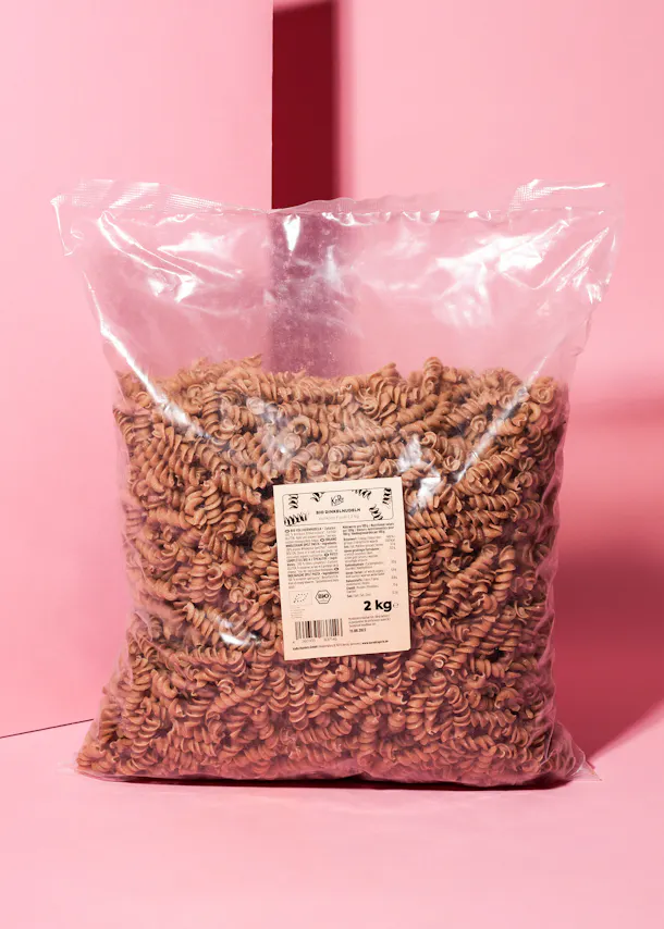 a bag of pasta is sitting on a pink surface
