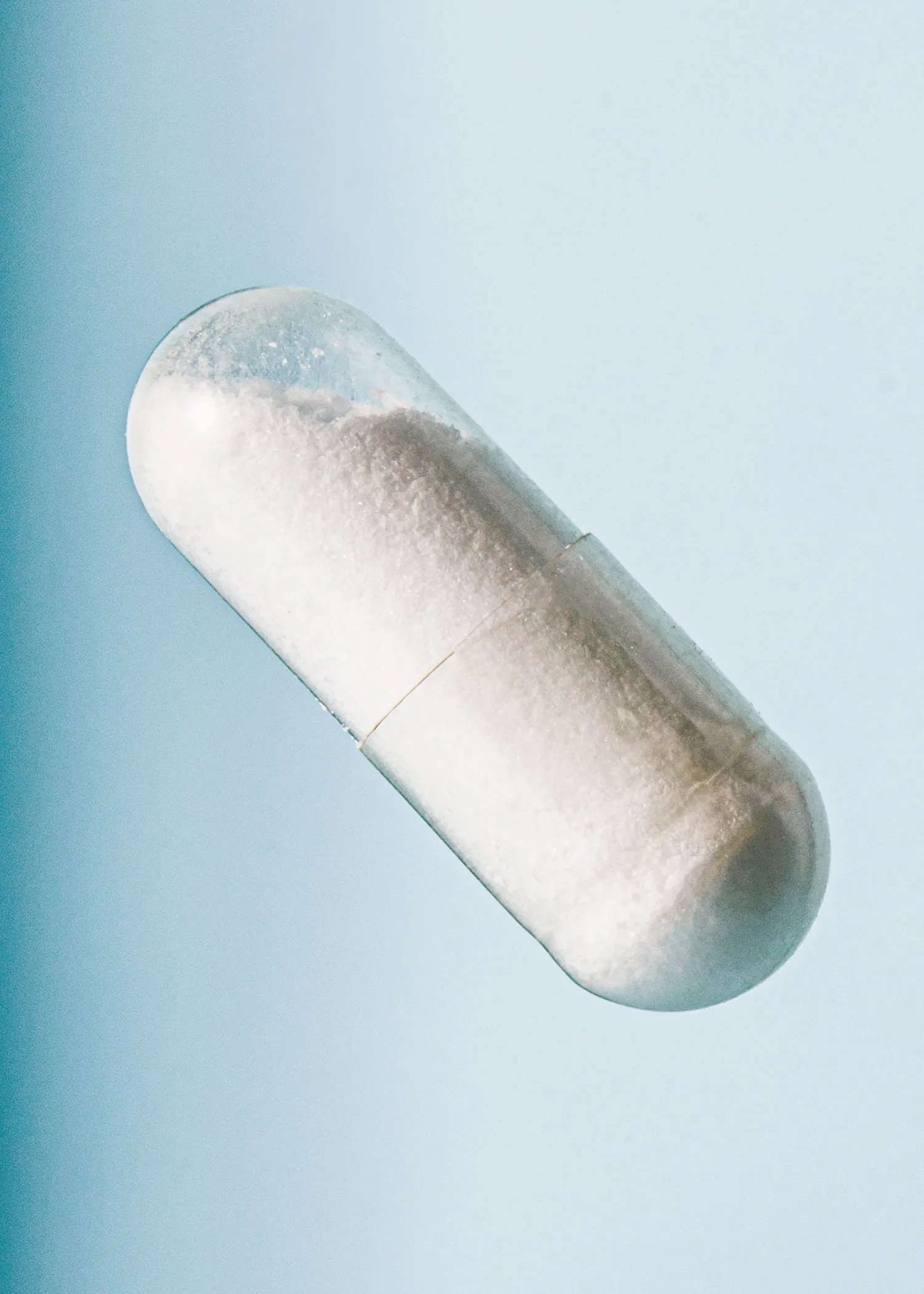 une capsule remplie de poudre blanche sur fond bleu
