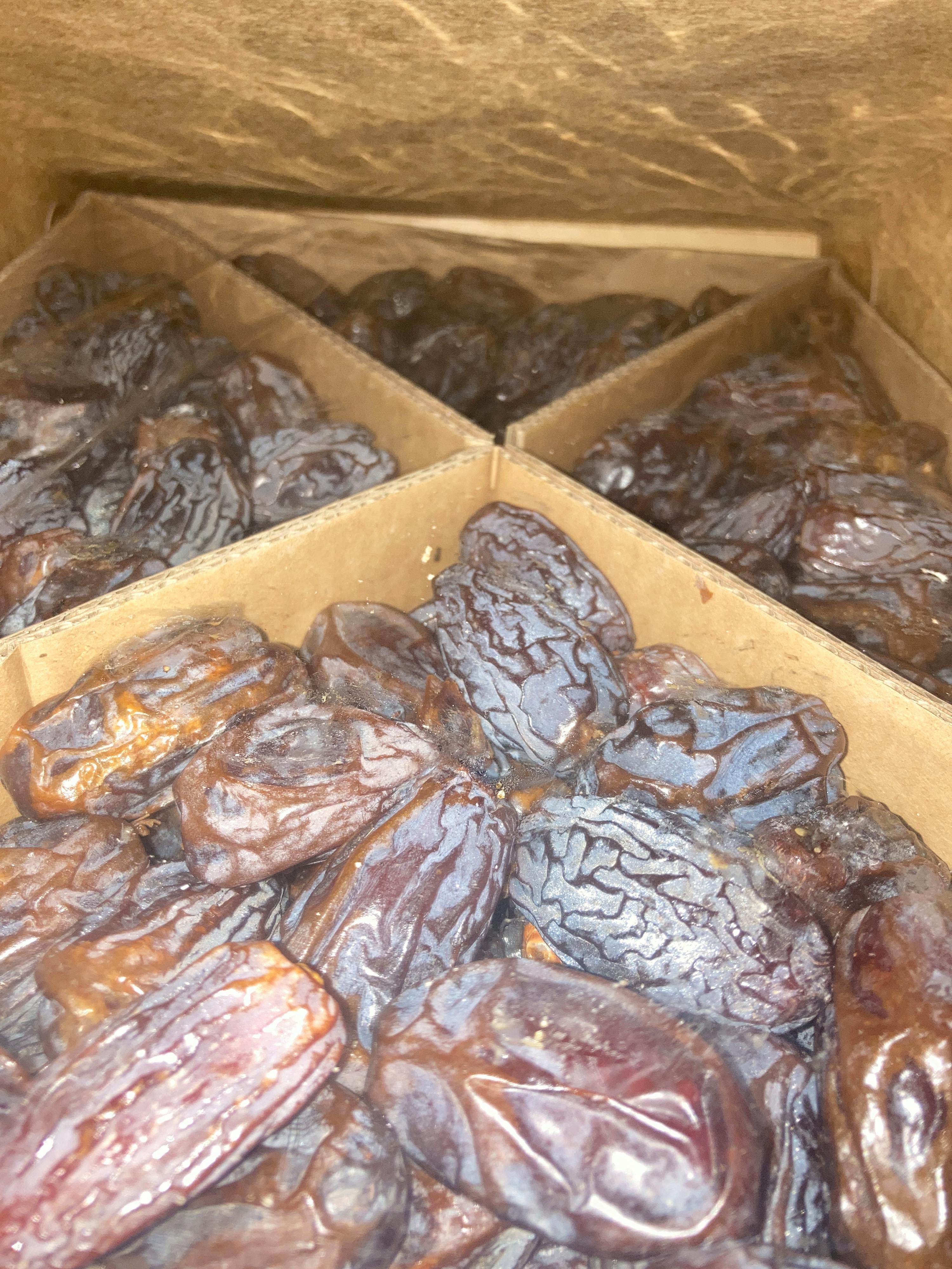 eine Schachtel mit braunen Datteln in einer Holzkiste