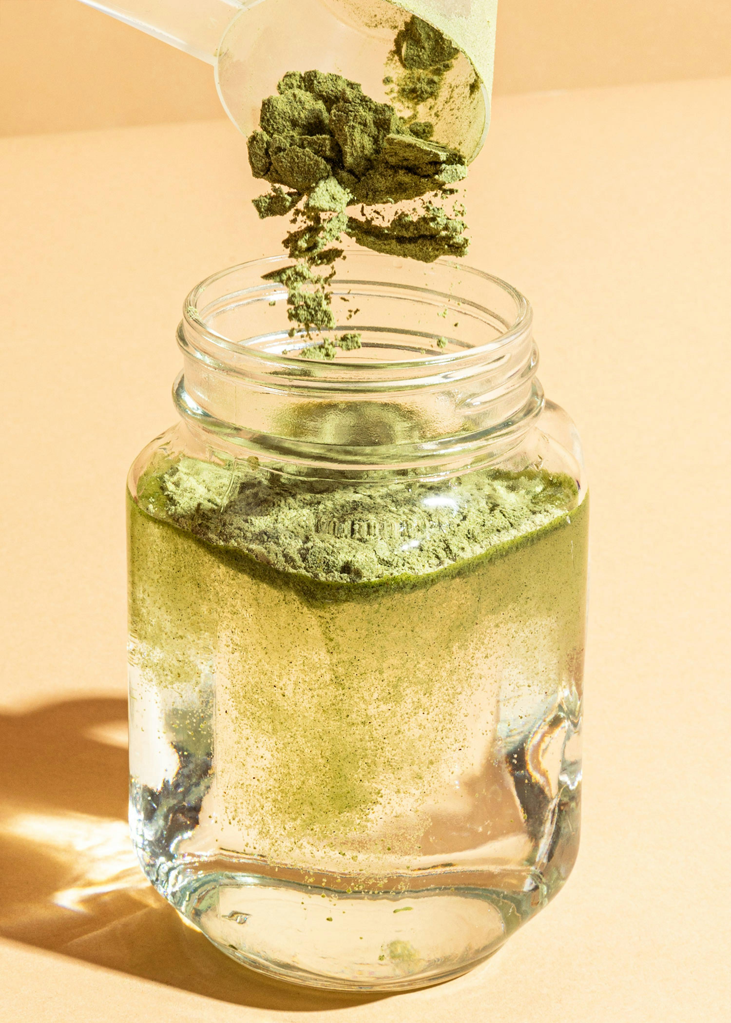eine Schüssel mit grünem pulver wird in ein Glas Wasser gefüllt