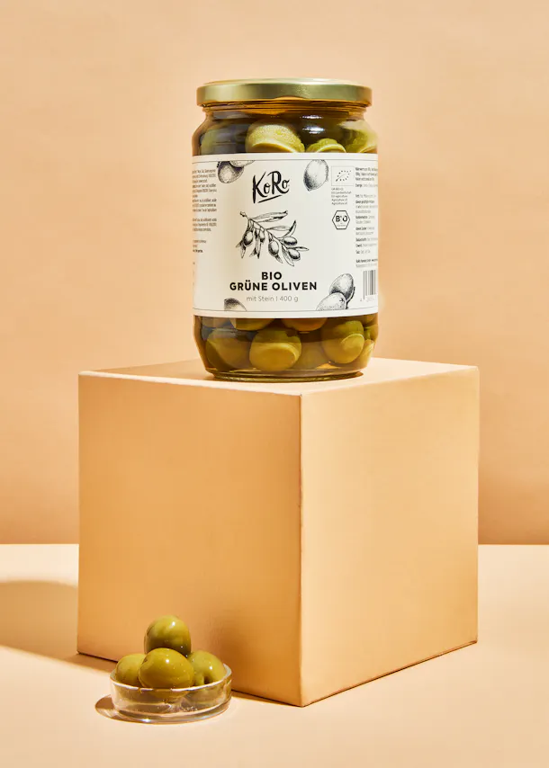 un bocal d' olives vertes bio est assis sur une boîte beige