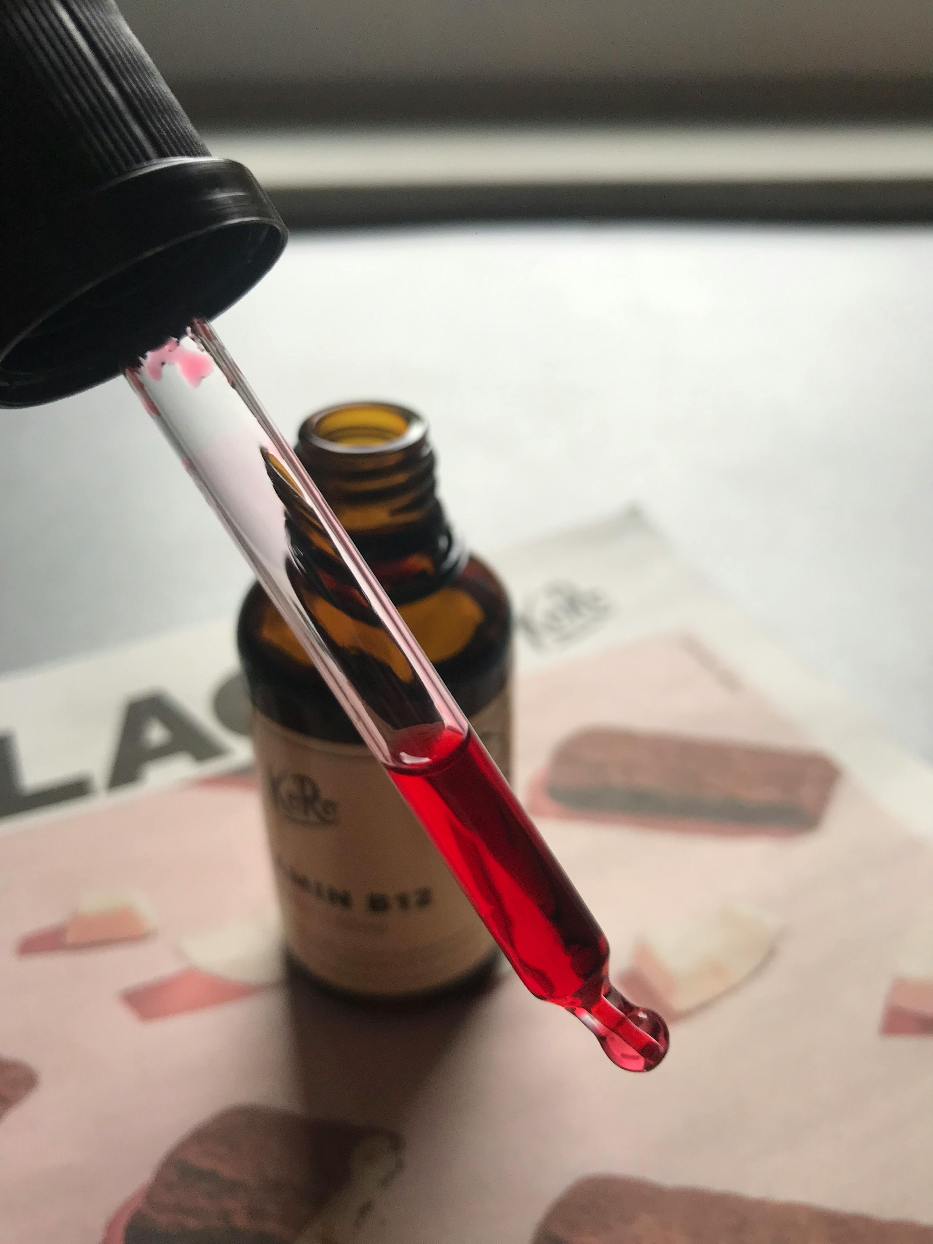 une pipette remplie d' un liquide rouge se trouve à côté d' une bouteille d' huile