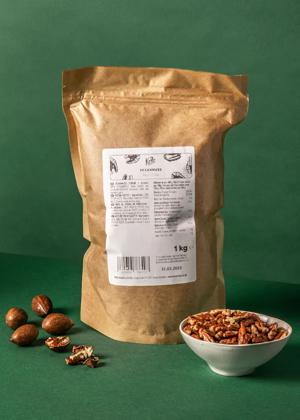 un sac de noix de pécan est assis sur une table verte à côté d' un bol de noix de pécan