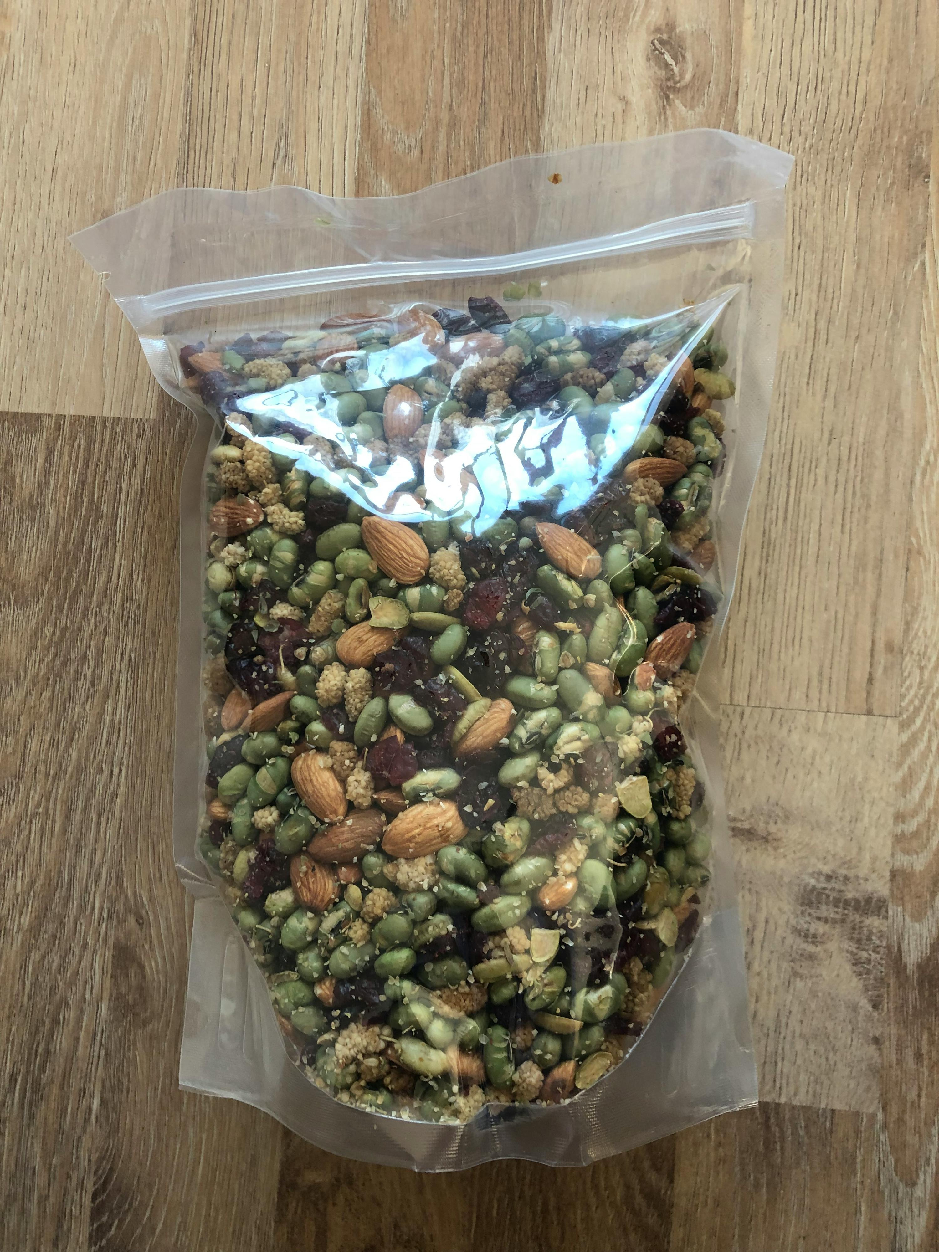 a plastic bag filled with nuts and seeds on a wooden table