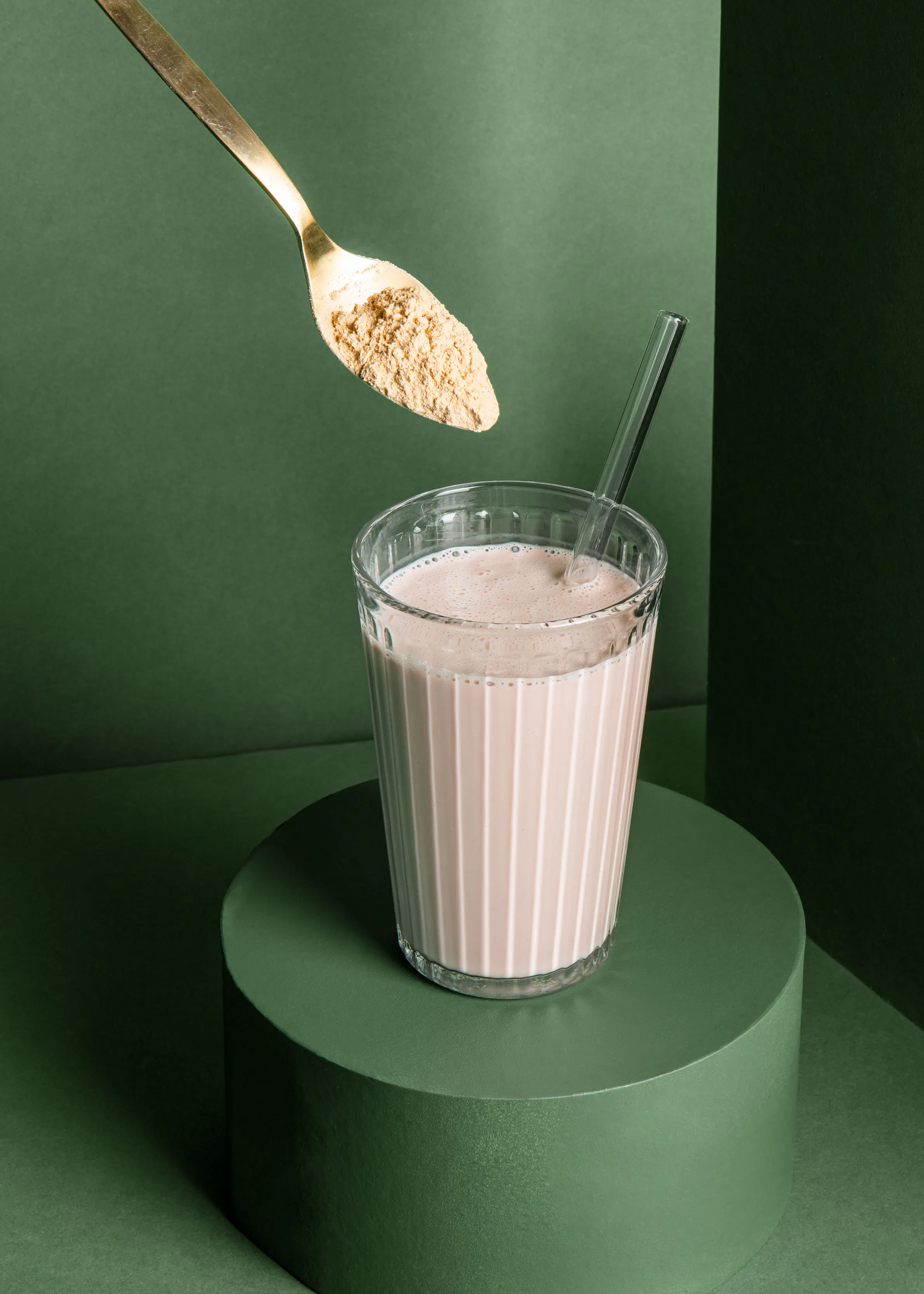 une cuillère est versée dans un verre de milkshake avec une paille