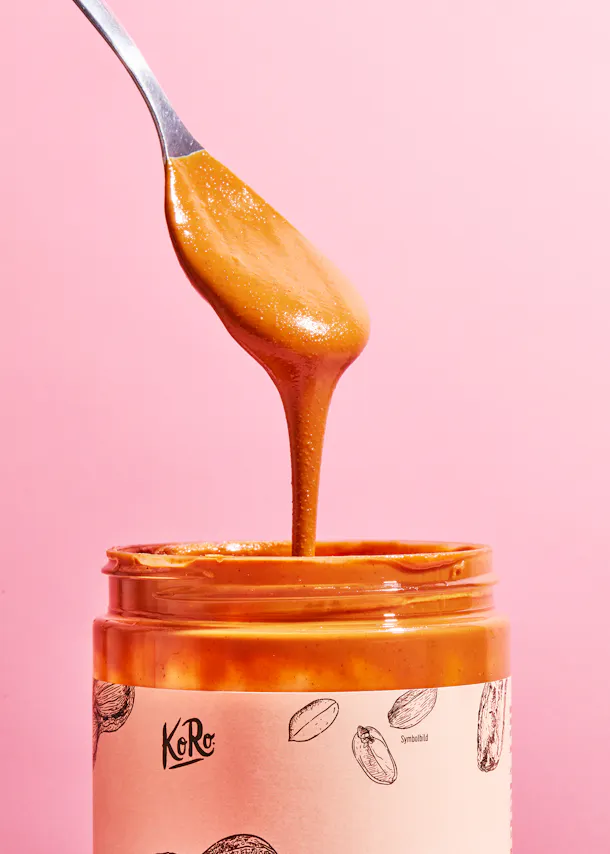une cuillère de beurre d' arachide est versée d' un bocal de beurre d' arachide