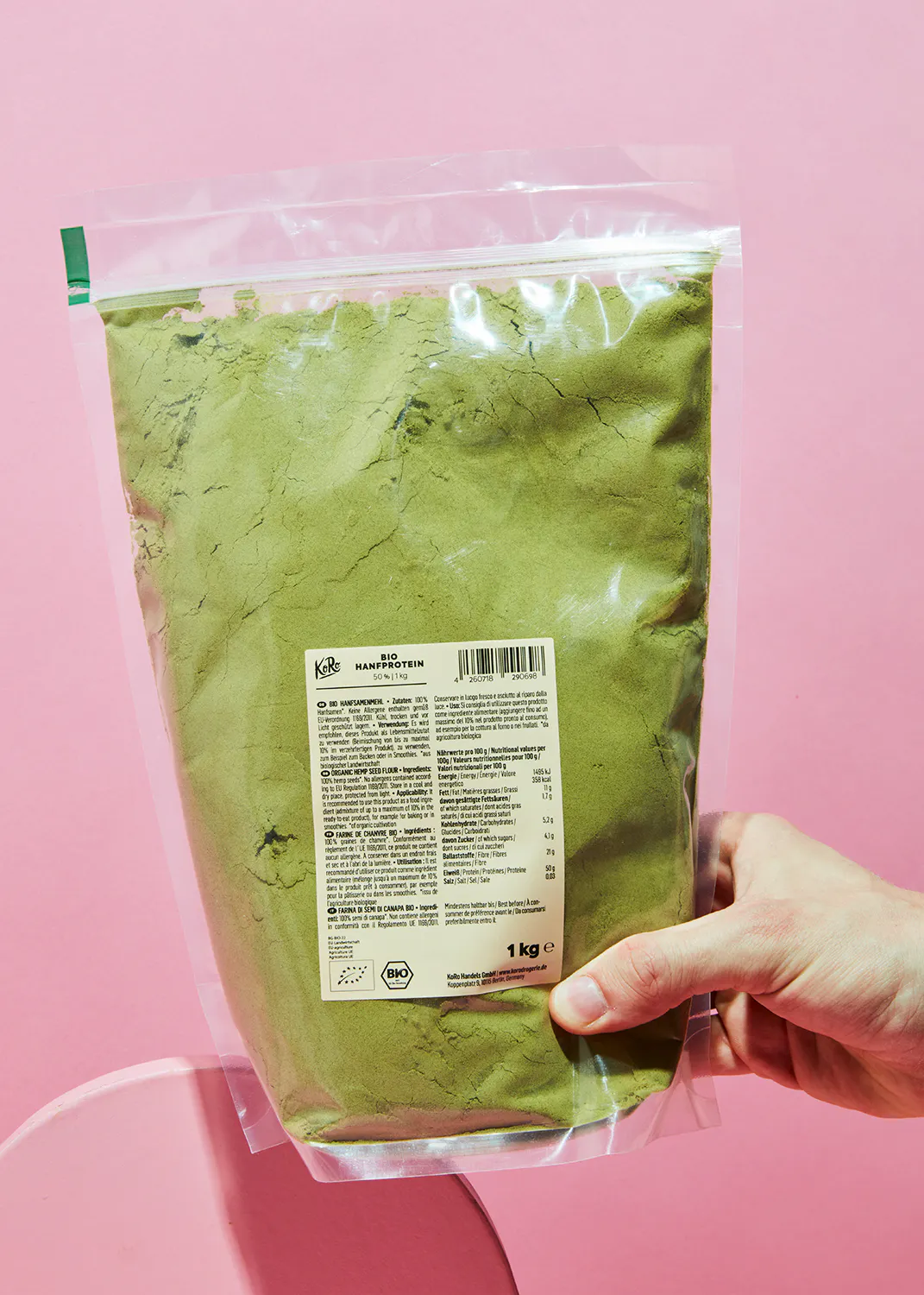 a person is holding a bag of green powder that says 1 kg