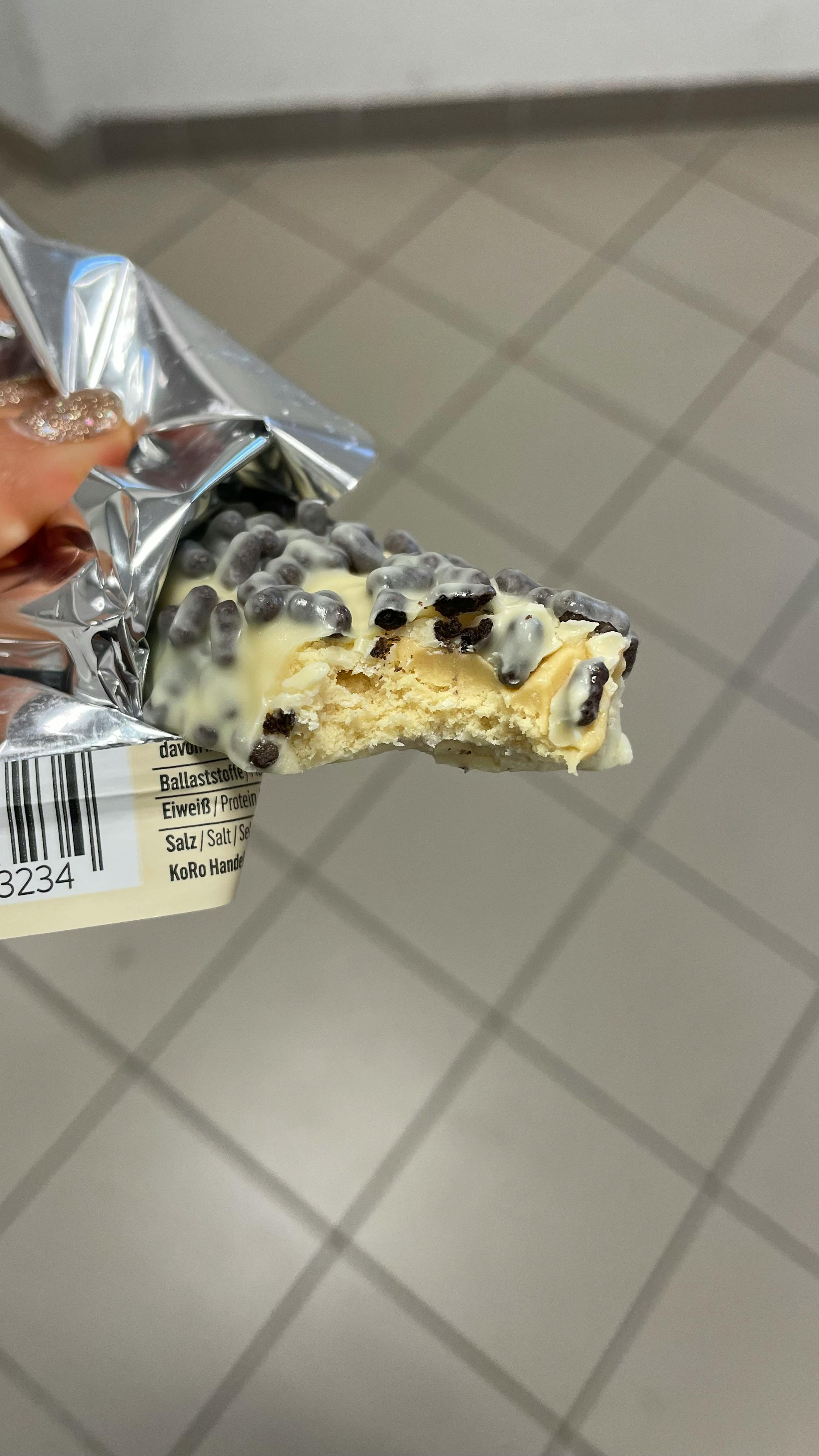 Eine Person hält eine Schokoladenstange mit einem Stück herausgenommen