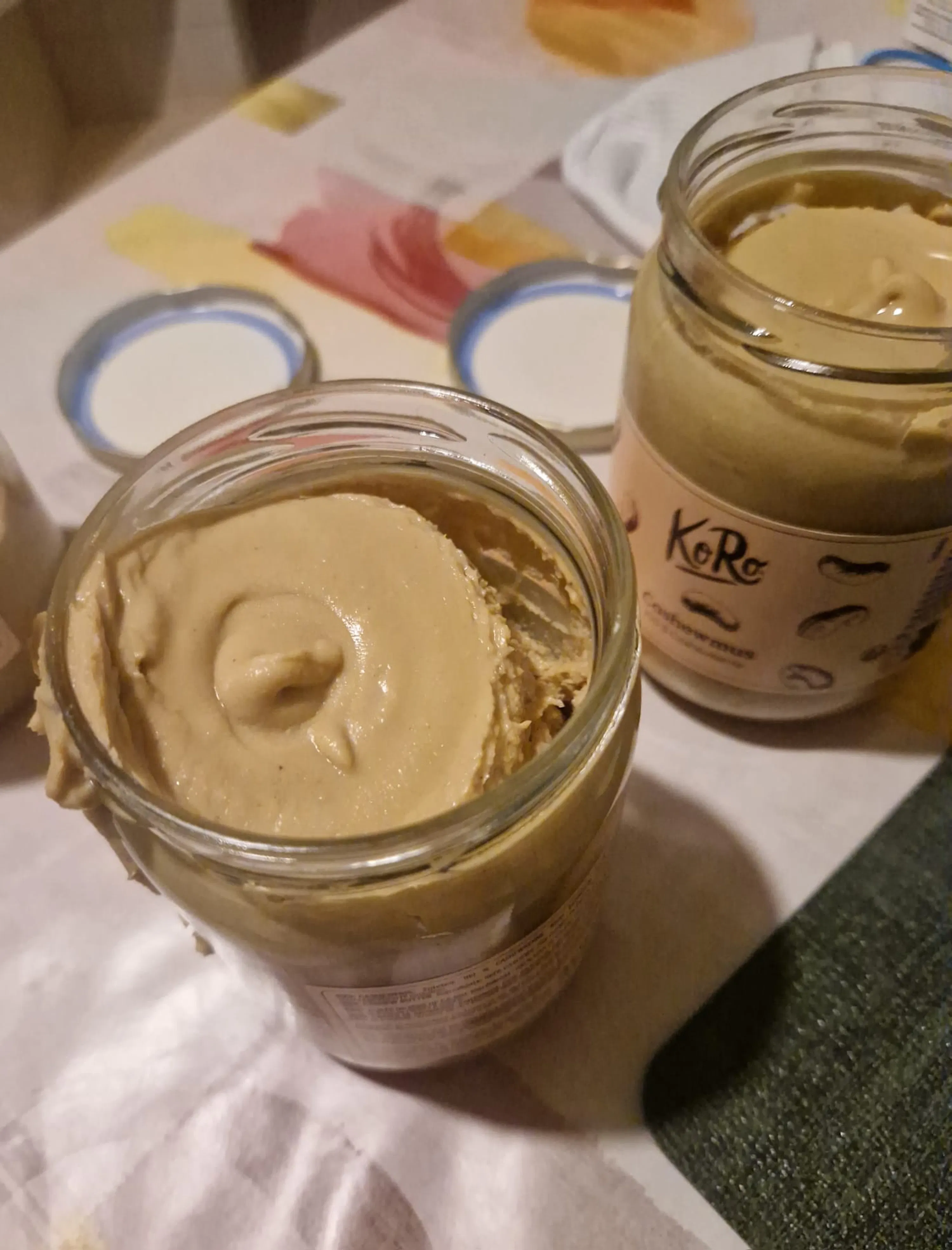 deux pots ouverts de beurre de cajou de la marque koro, l'un partiellement utilisé au premier plan et l'autre en arrière-plan.