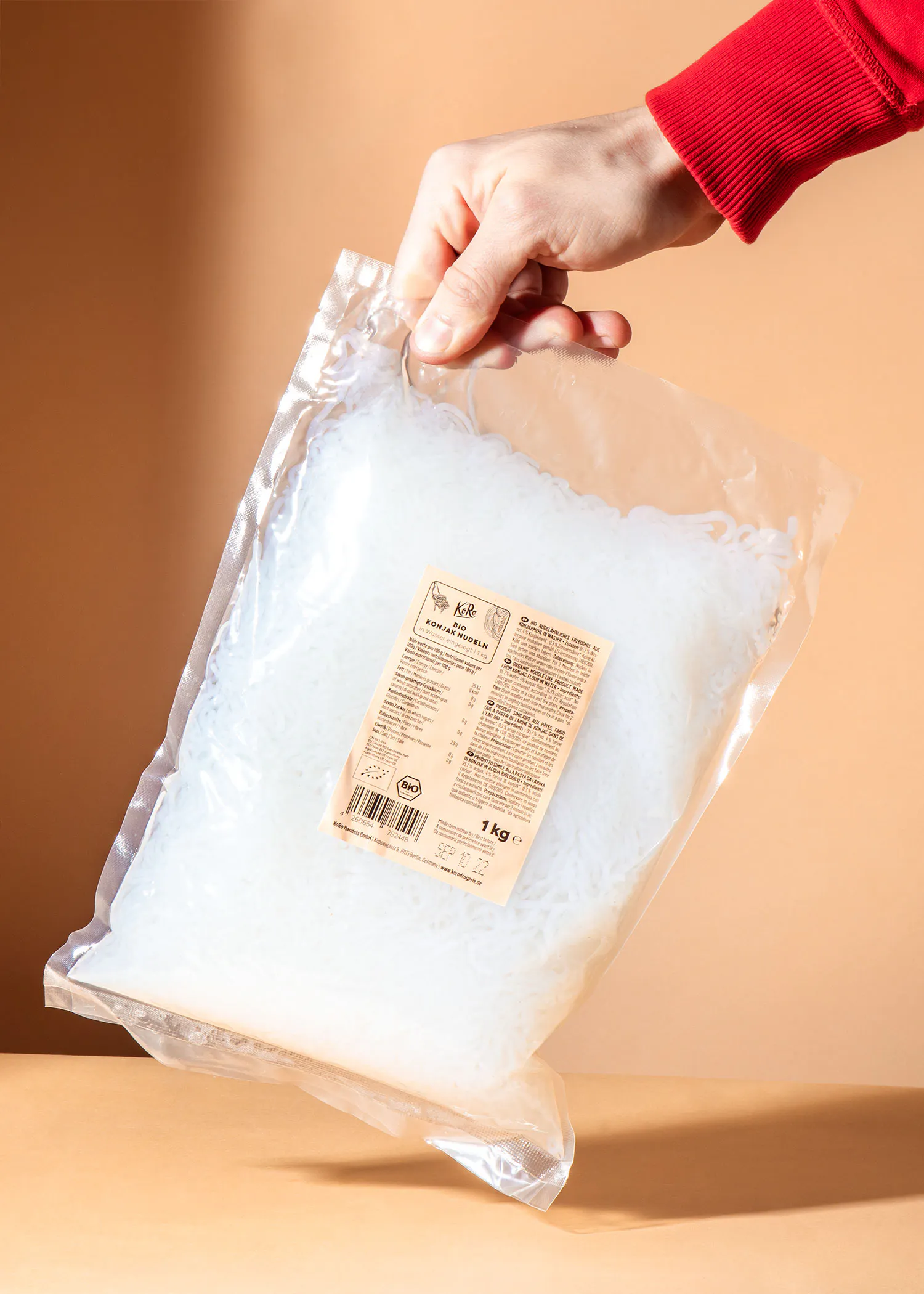 une personne tient un sac de nouilles avec une étiquette qui dit 1 kg