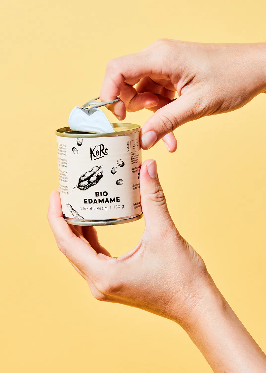 a person is opening a can of koro bio edamame