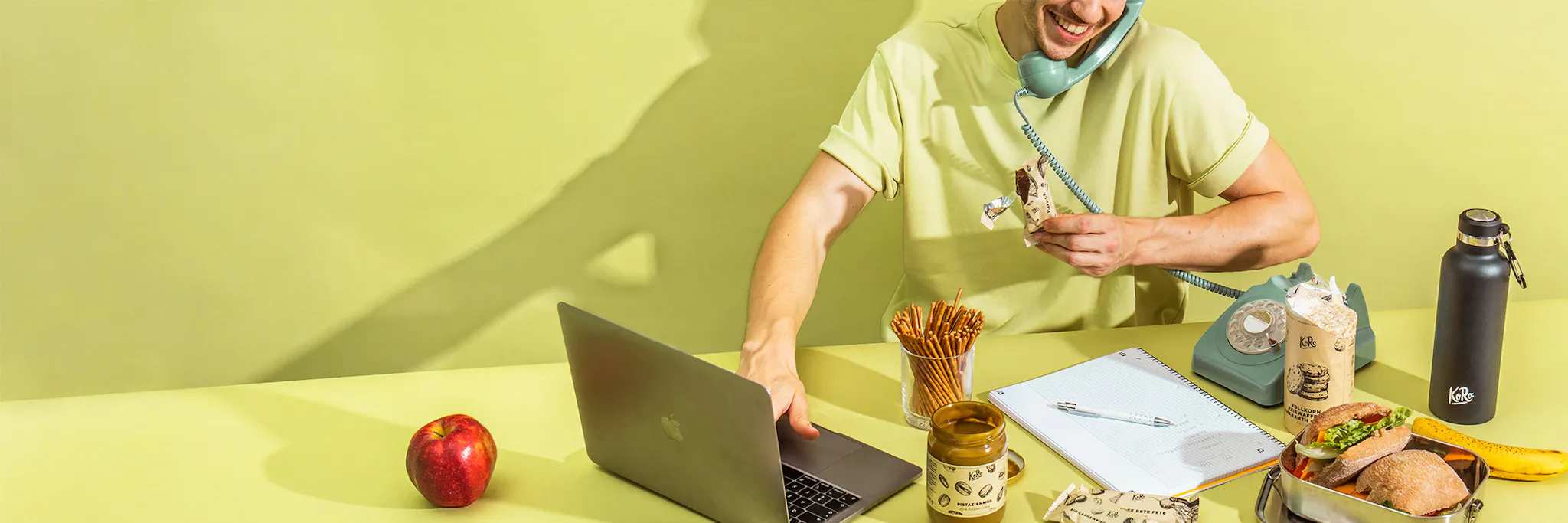 un homme est assis à une table avec un ordinateur portable et une pomme