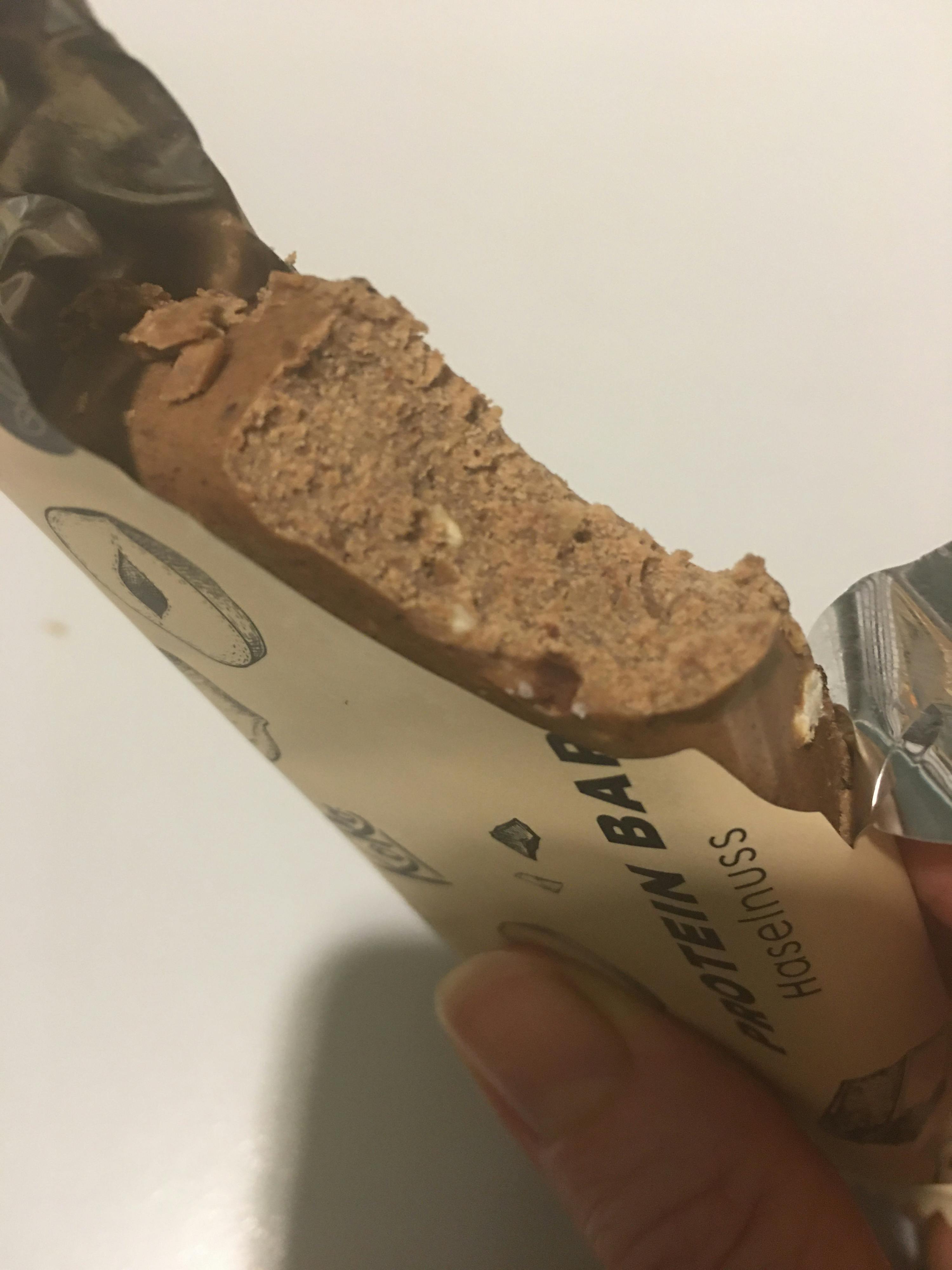 eine person hält einen protein bar mit einem stück genommen
