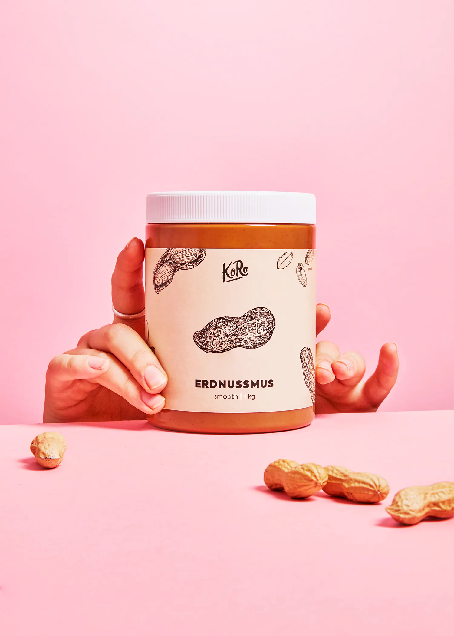 une personne tient un bocal de beurre d' arachide sur fond rose