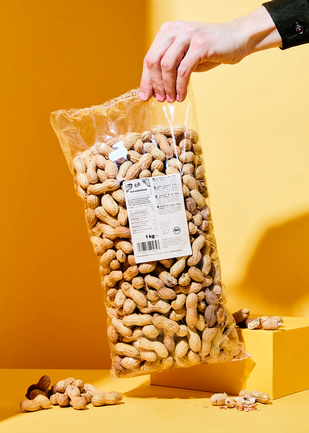 una persona sostiene una bolsa de cacahuetes de 1 kg