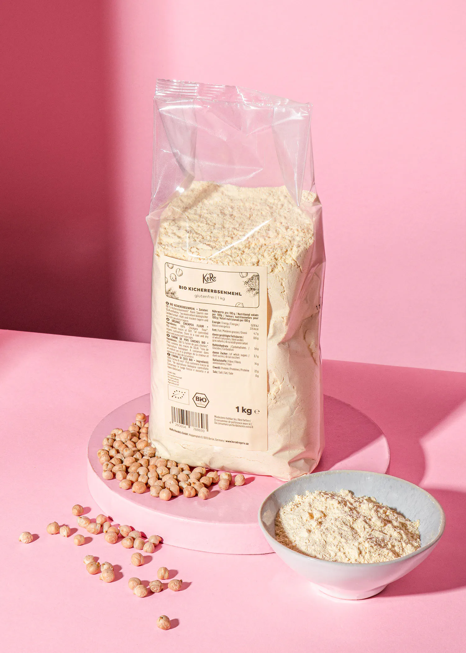 un sac de farine de pois assis sur une table rose à côté d' un bol de farine