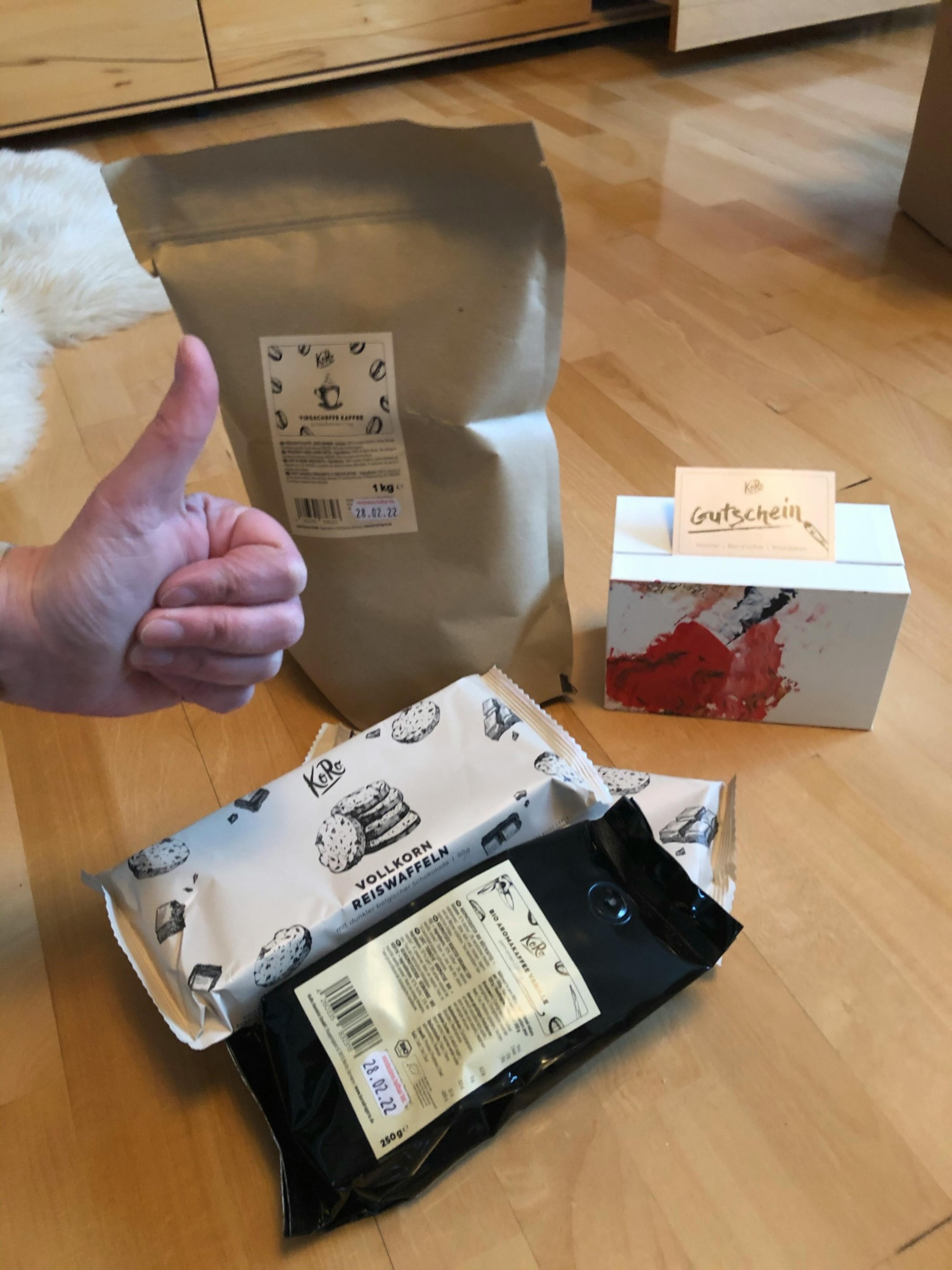 a person giving a thumbs up next to a bag of kaffee