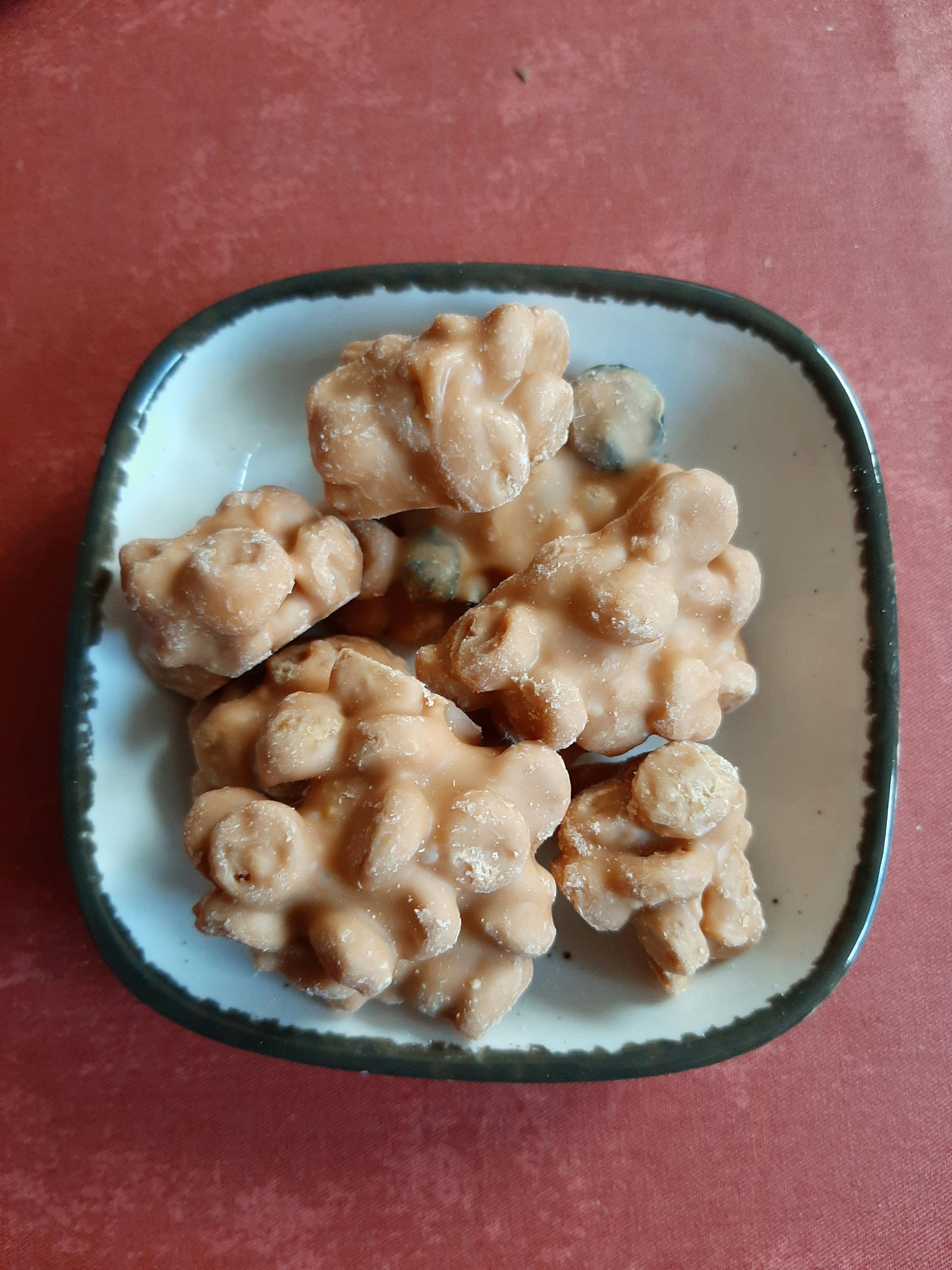 a bowl filled with nuts covered in icing on a red surface