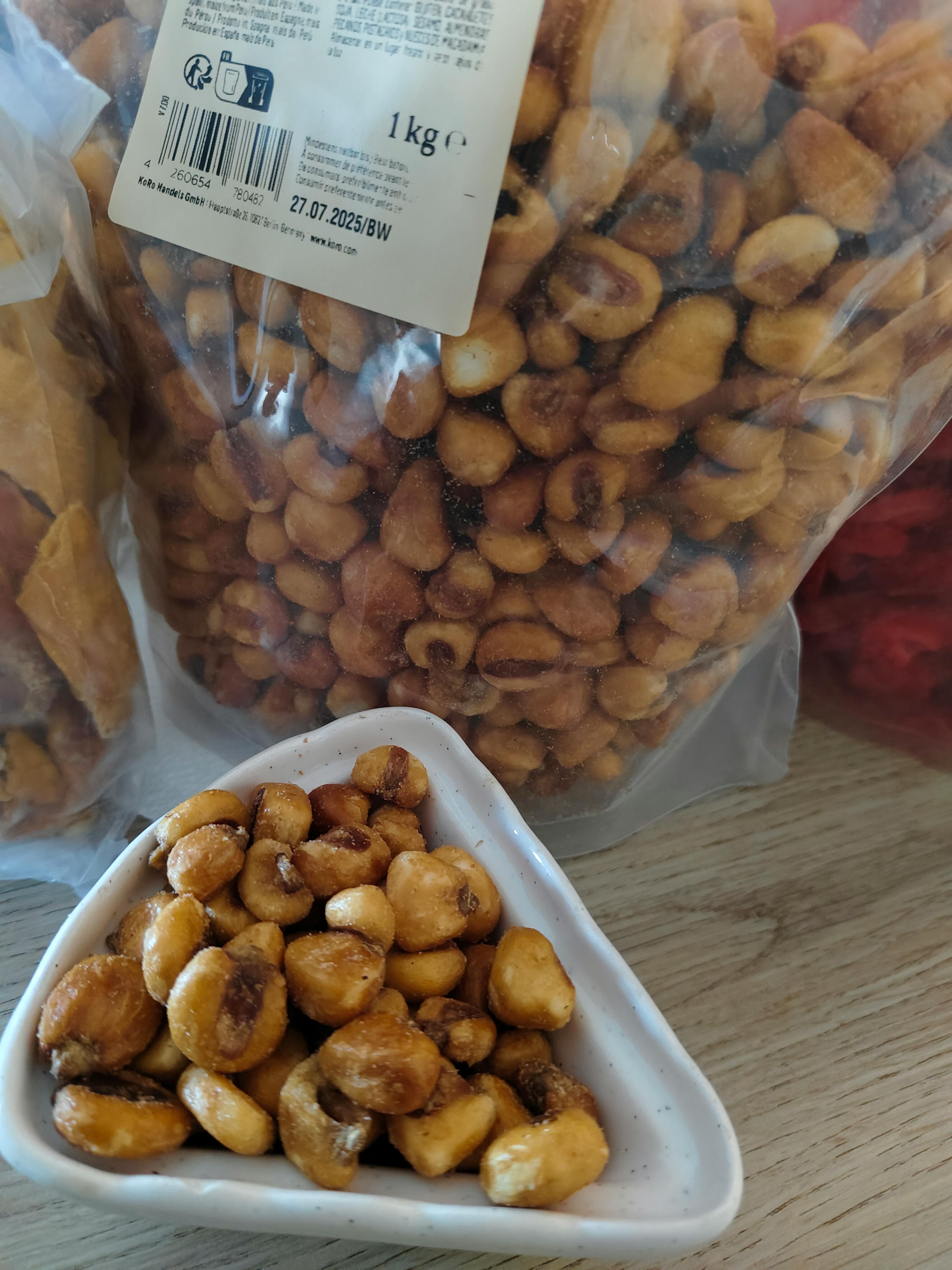 ein weißer Teller mit Maiskörnern neben einem Plastikbeutel mit Maiskörnern