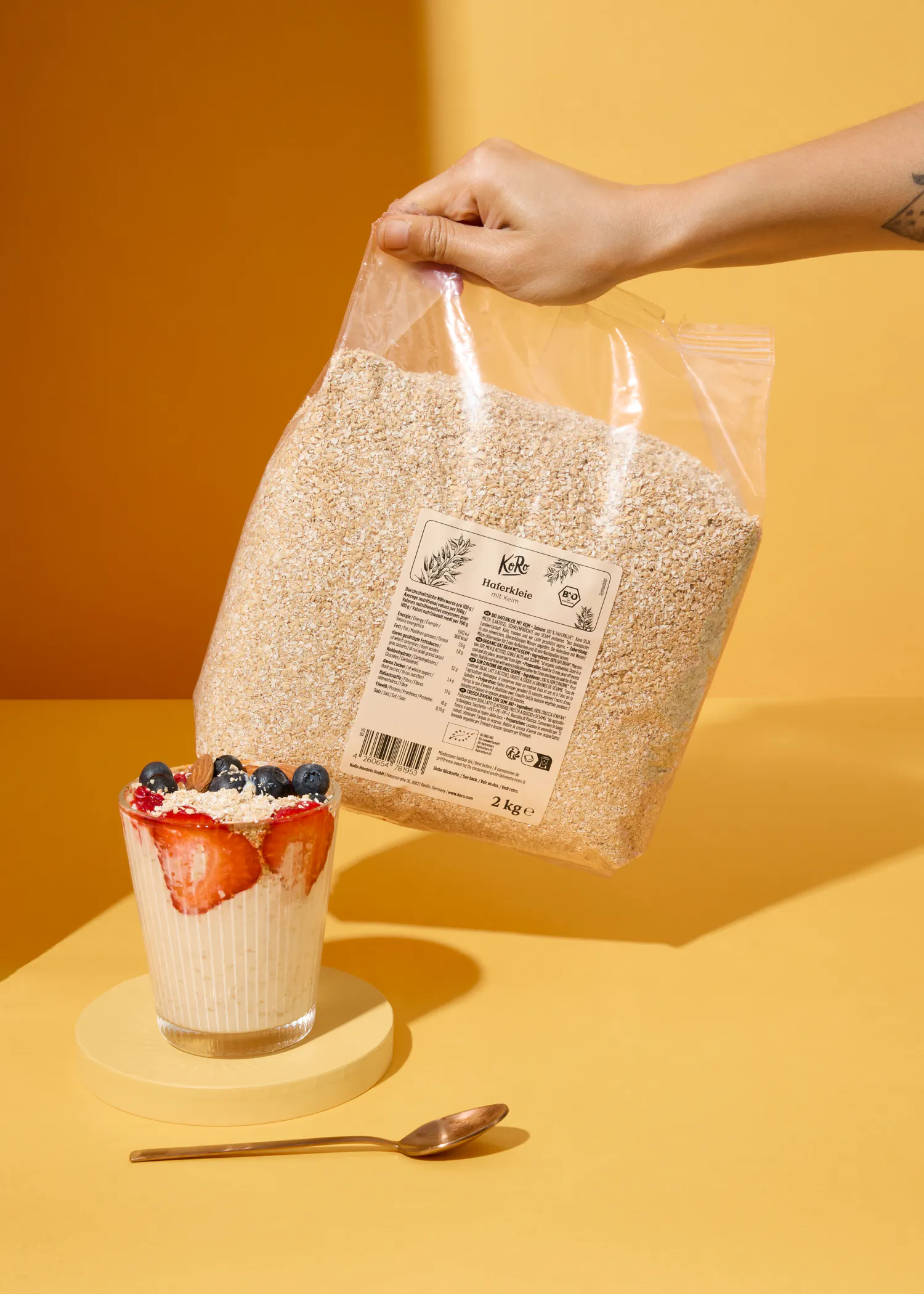 eine Person hält eine Tüte Haferflocken neben einem Glas Haferflocken