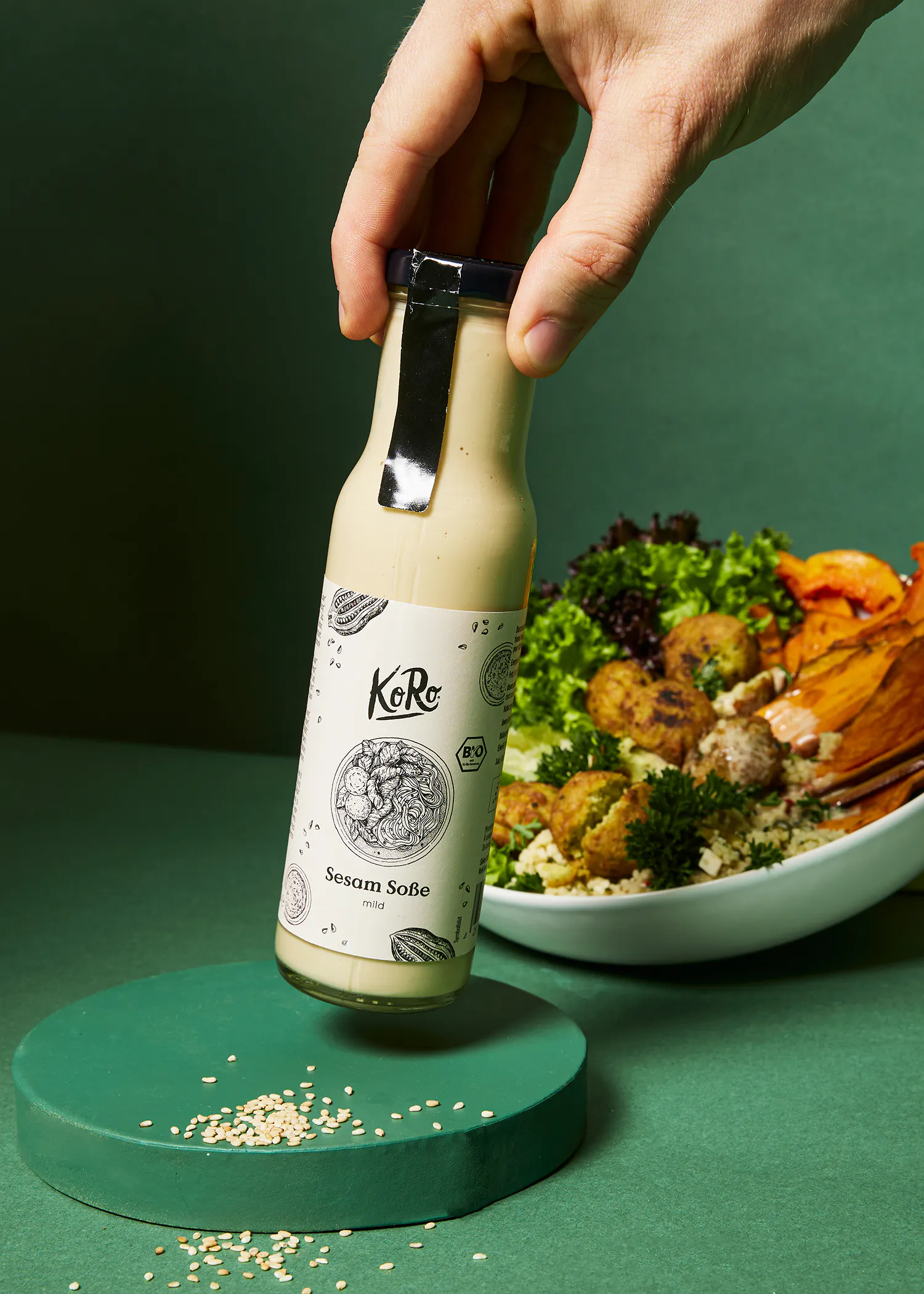 una persona sostiene una botella de salsa de sésamo frente a un plato de ensalada