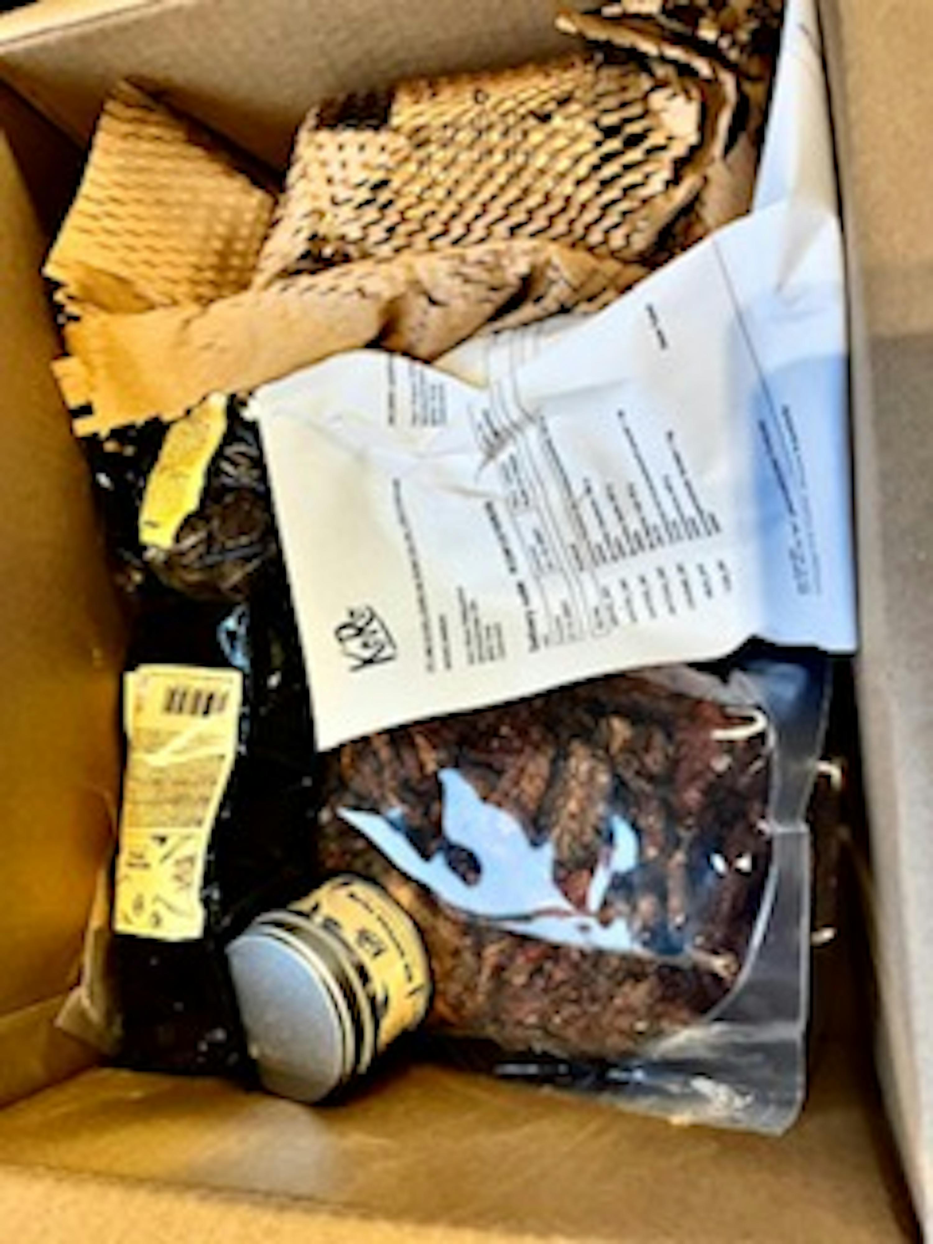 a cardboard box filled with a bottle and a bag of pecans