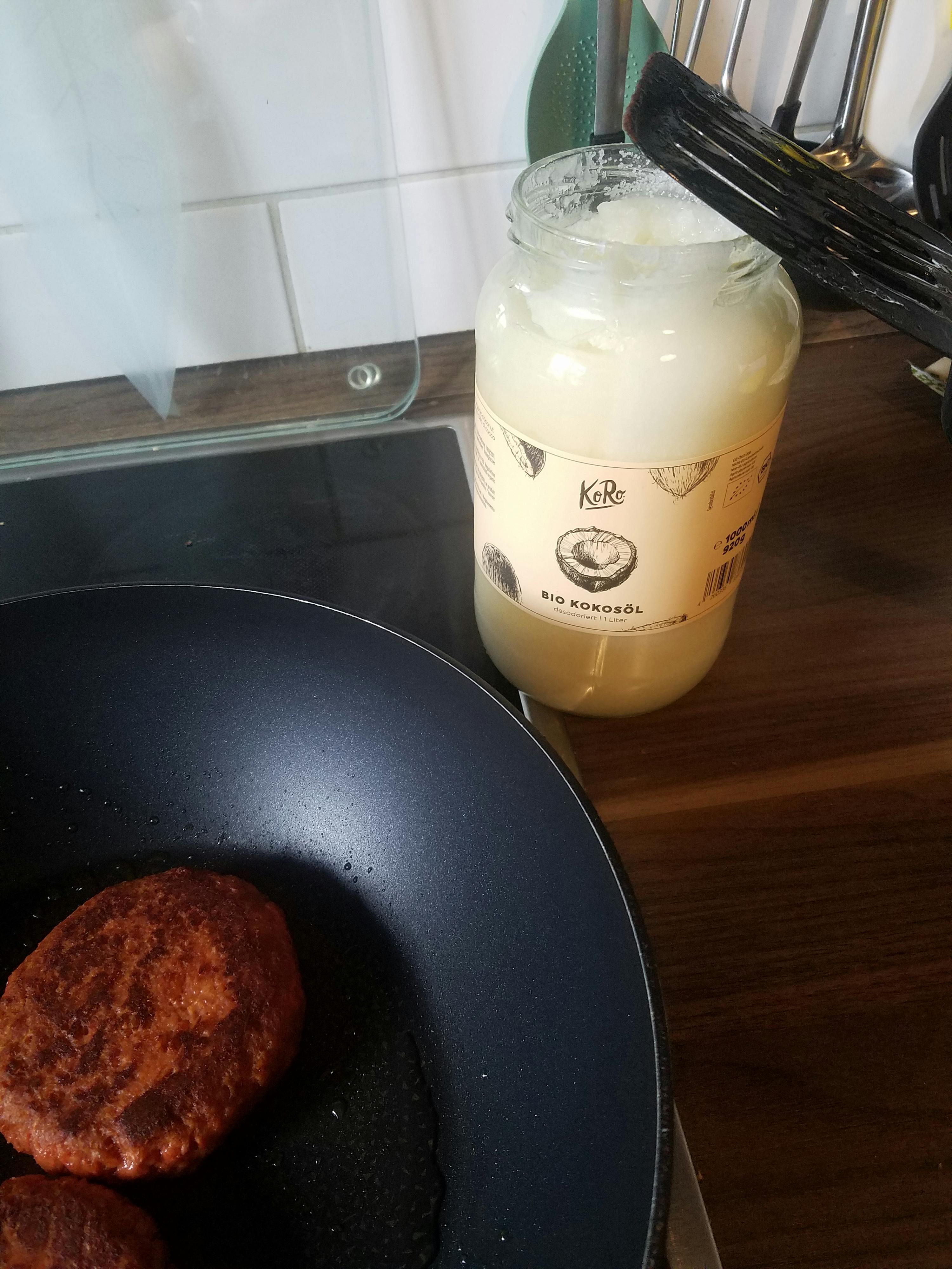 a jar of coconut oil sits on a counter next to a frying pan