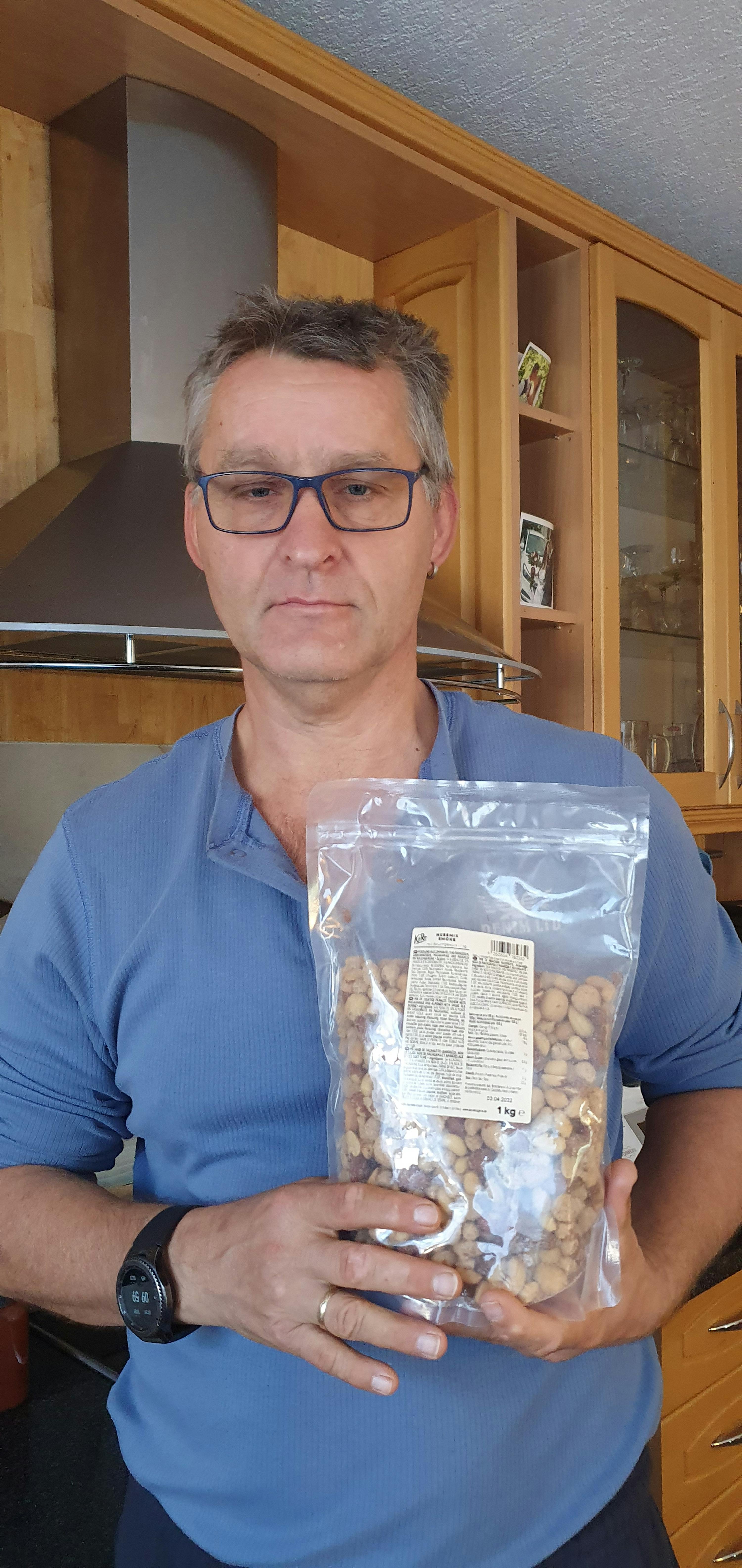 un uomo con gli occhiali tiene in mano un sacchetto di noci