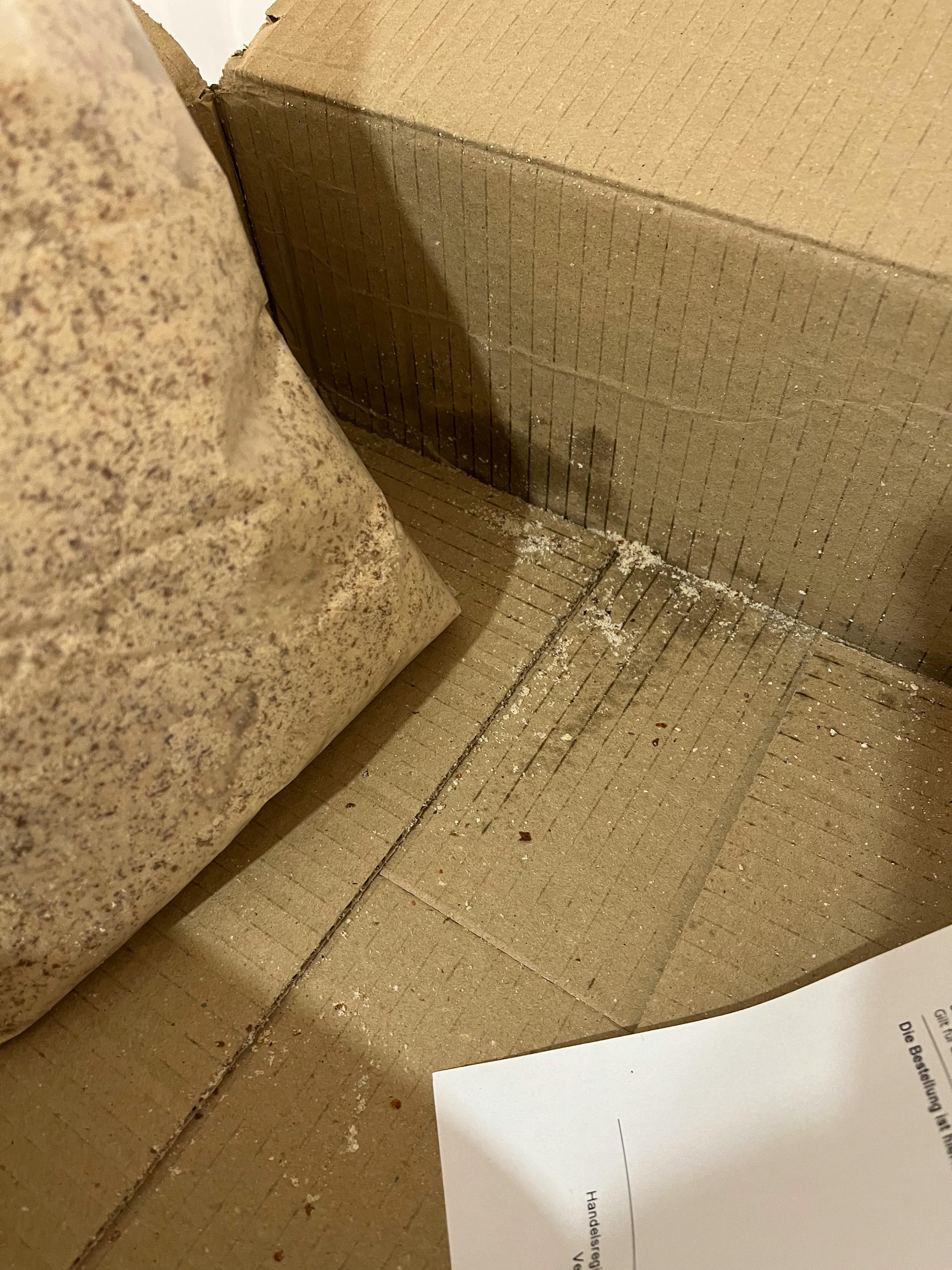 una scatola di cartone con un sacchetto di polvere e un foglio di carta con l' indirizzo di spedizione