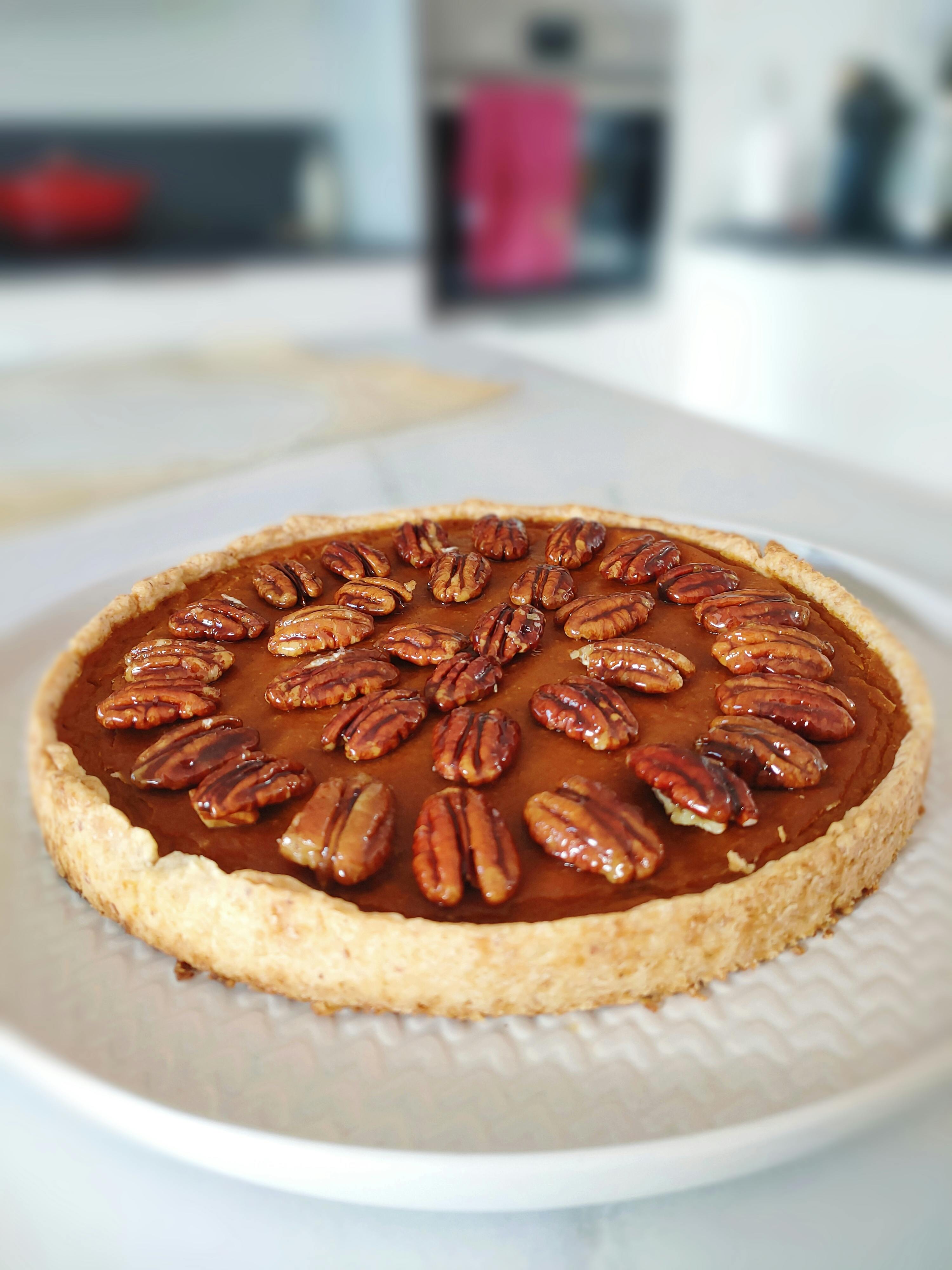 a pie with pecans on top is on a white plate