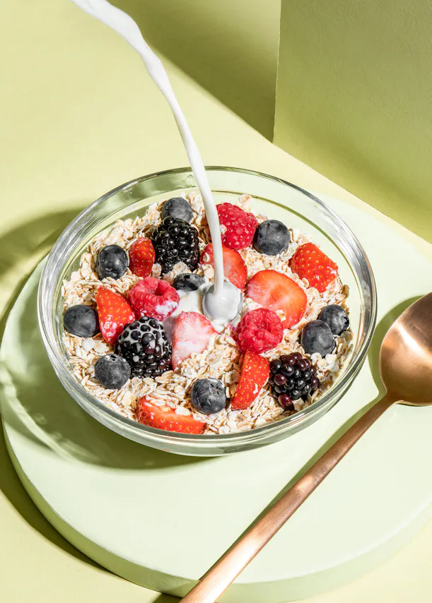 un bol d' avoine avec des baies et du lait versé