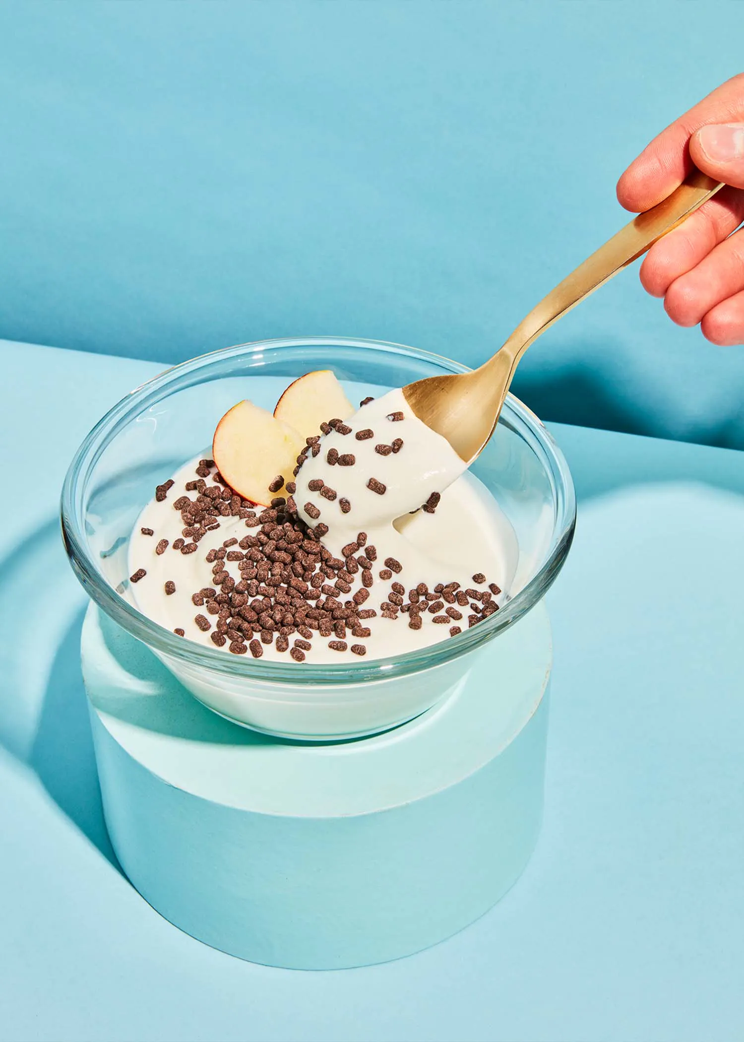 une cuillère est prise d' un bol de yogourt avec des pépites de chocolat et des tranches de pomme