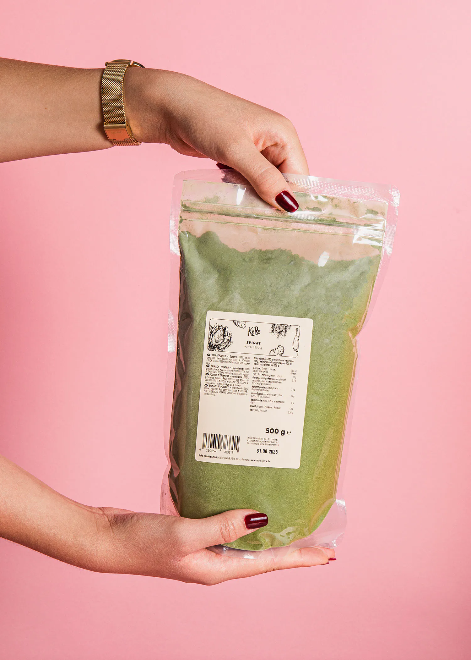 une femme tient un sac de poudre d' épinards sur fond rose