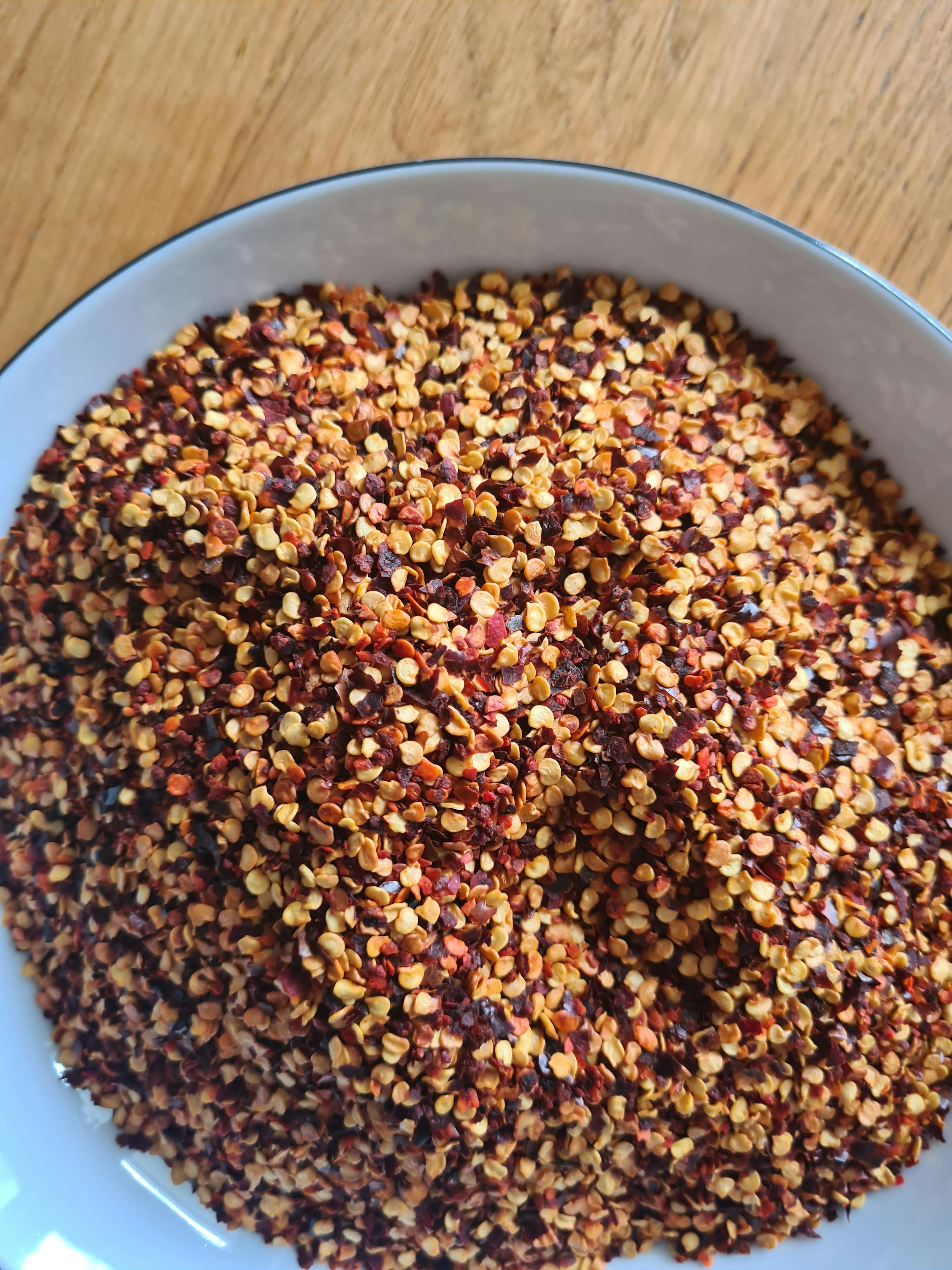 a white bowl filled with red and yellow pepper flakes