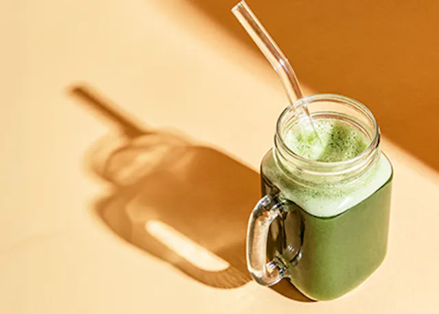 ein grüner Smoothie in einem Einmachglas mit einem Strohhalm