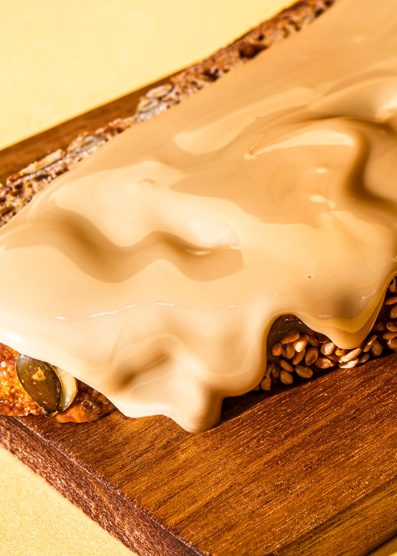 ein Stück Brot mit Erdnussbutter darauf auf einem Holzbrett