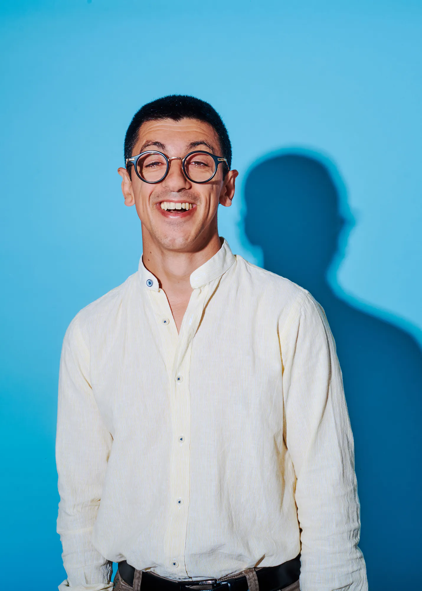 un homme portant des lunettes et une chemise blanche sourit
