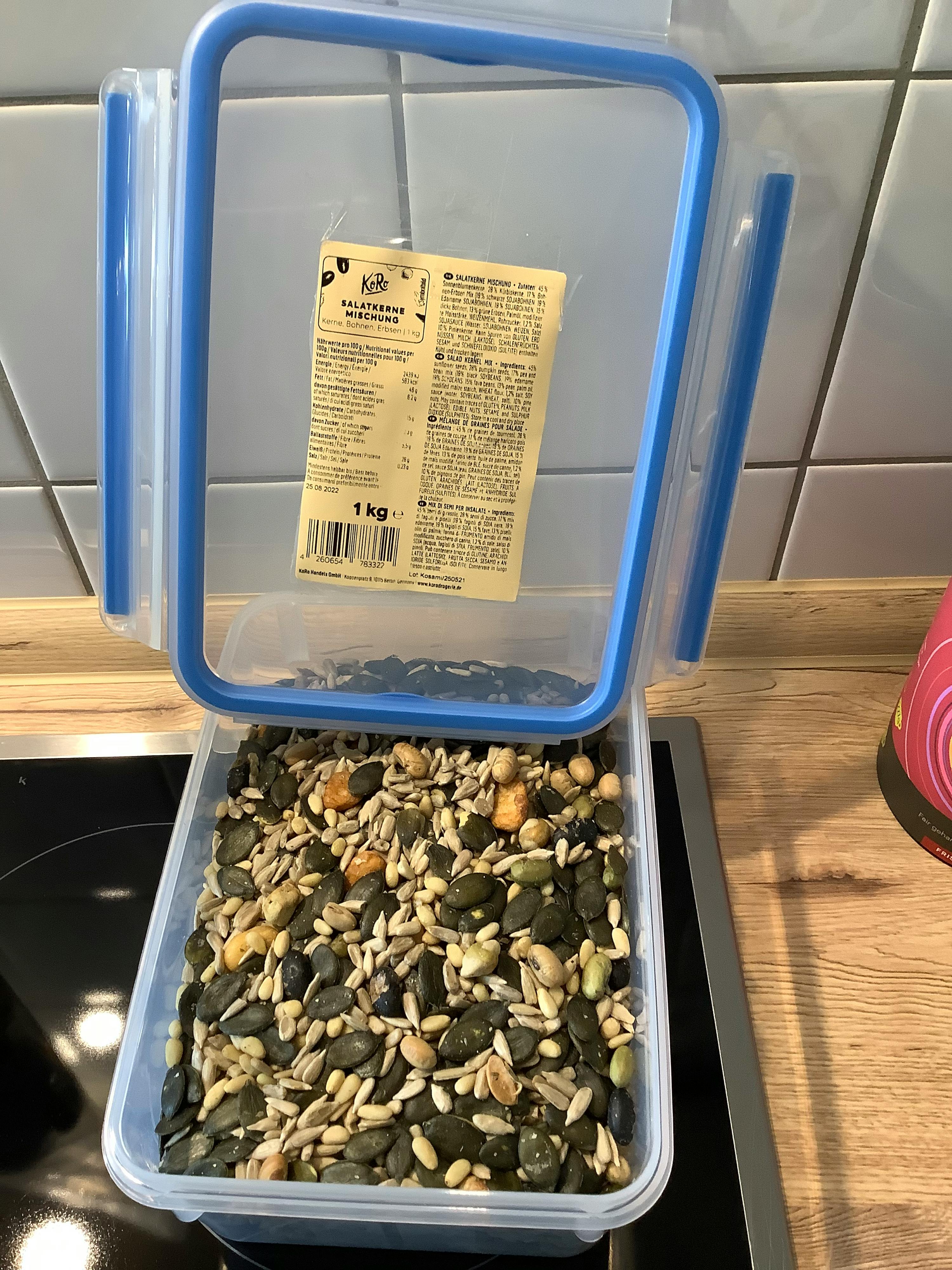 a blue plastic container filled with nuts and seeds