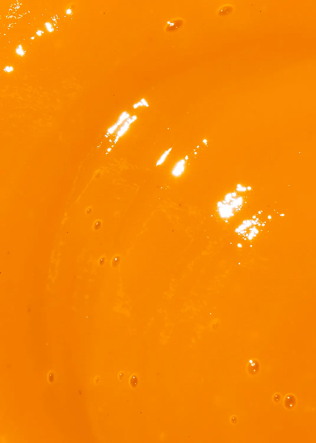 un gros plan d' un liquide orange avec des bulles visibles